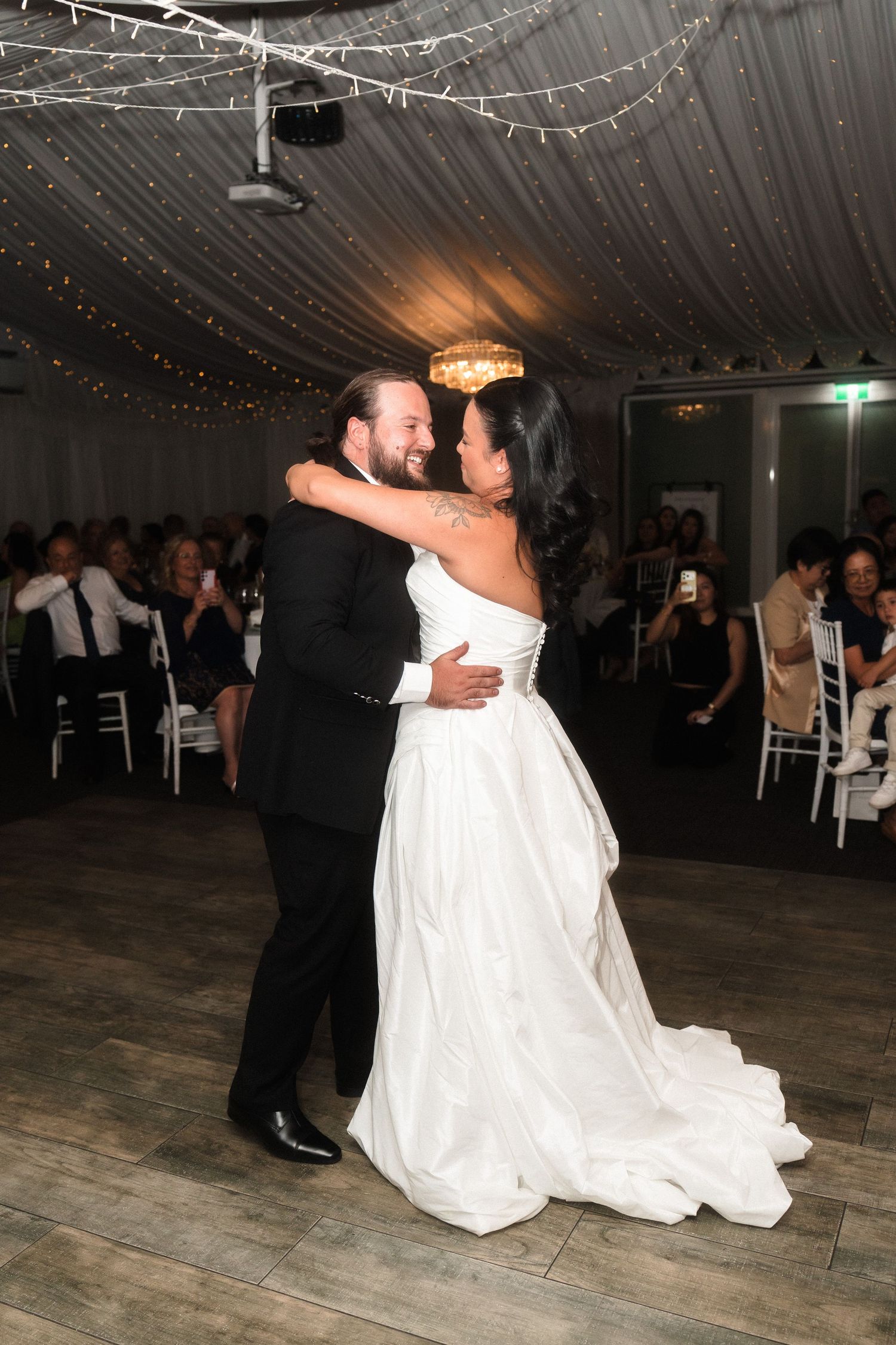 Couple shares first dance under twinkling lights at wedding reception.