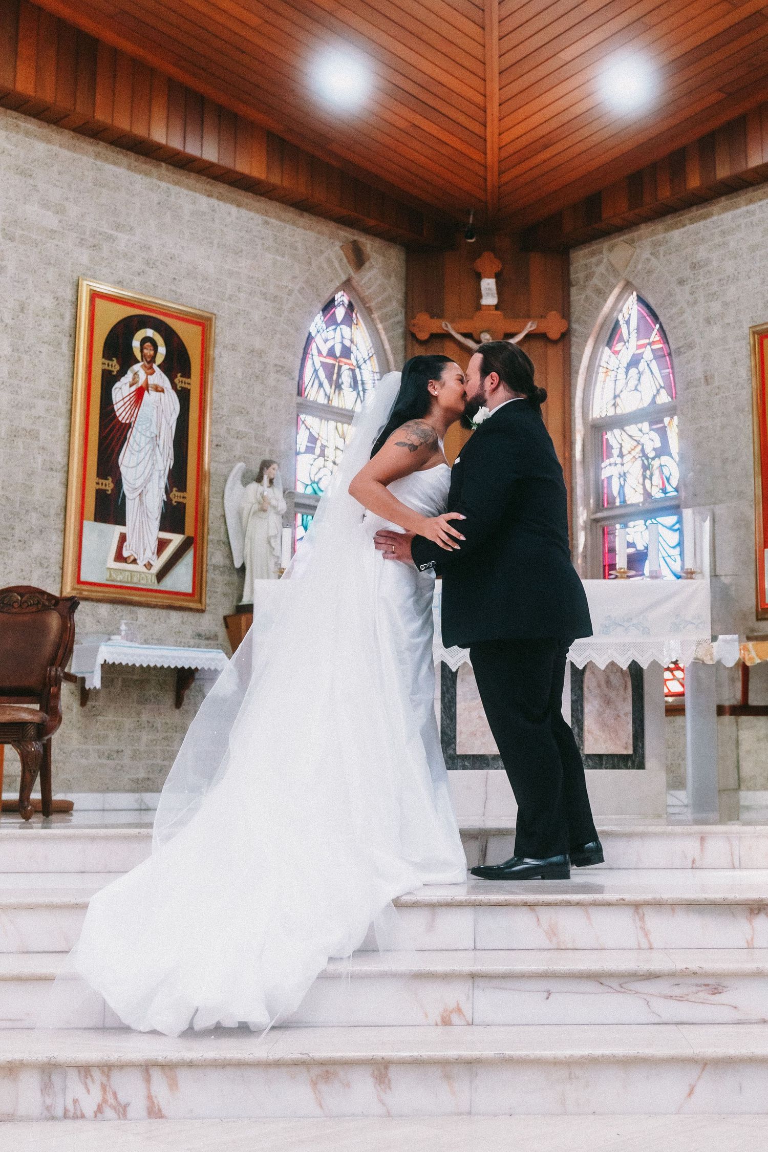 Wedding couple shares romantic dance moves on church altar steps.