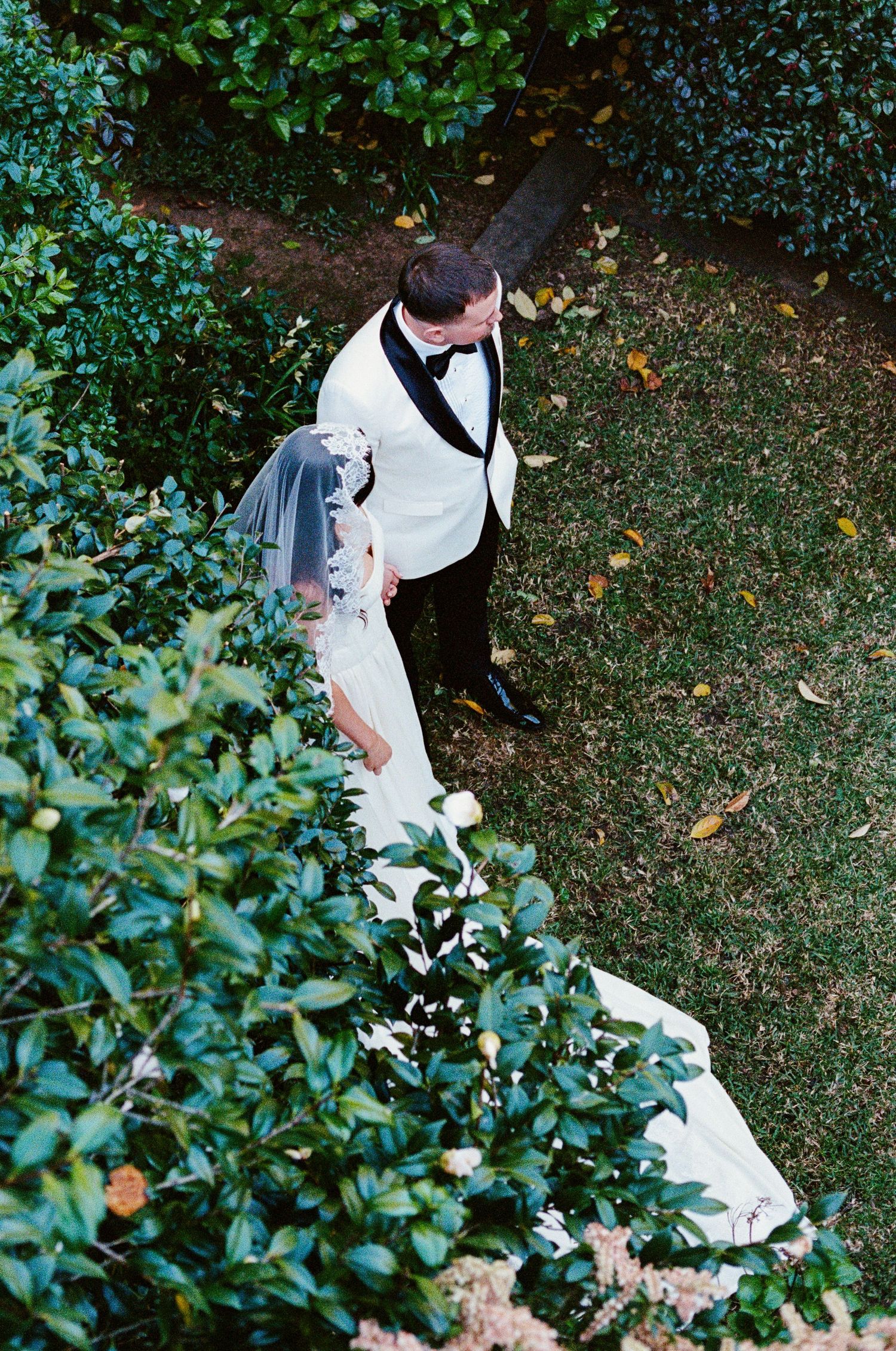 A couple walks through a garden setting during their wedding photoshoot.