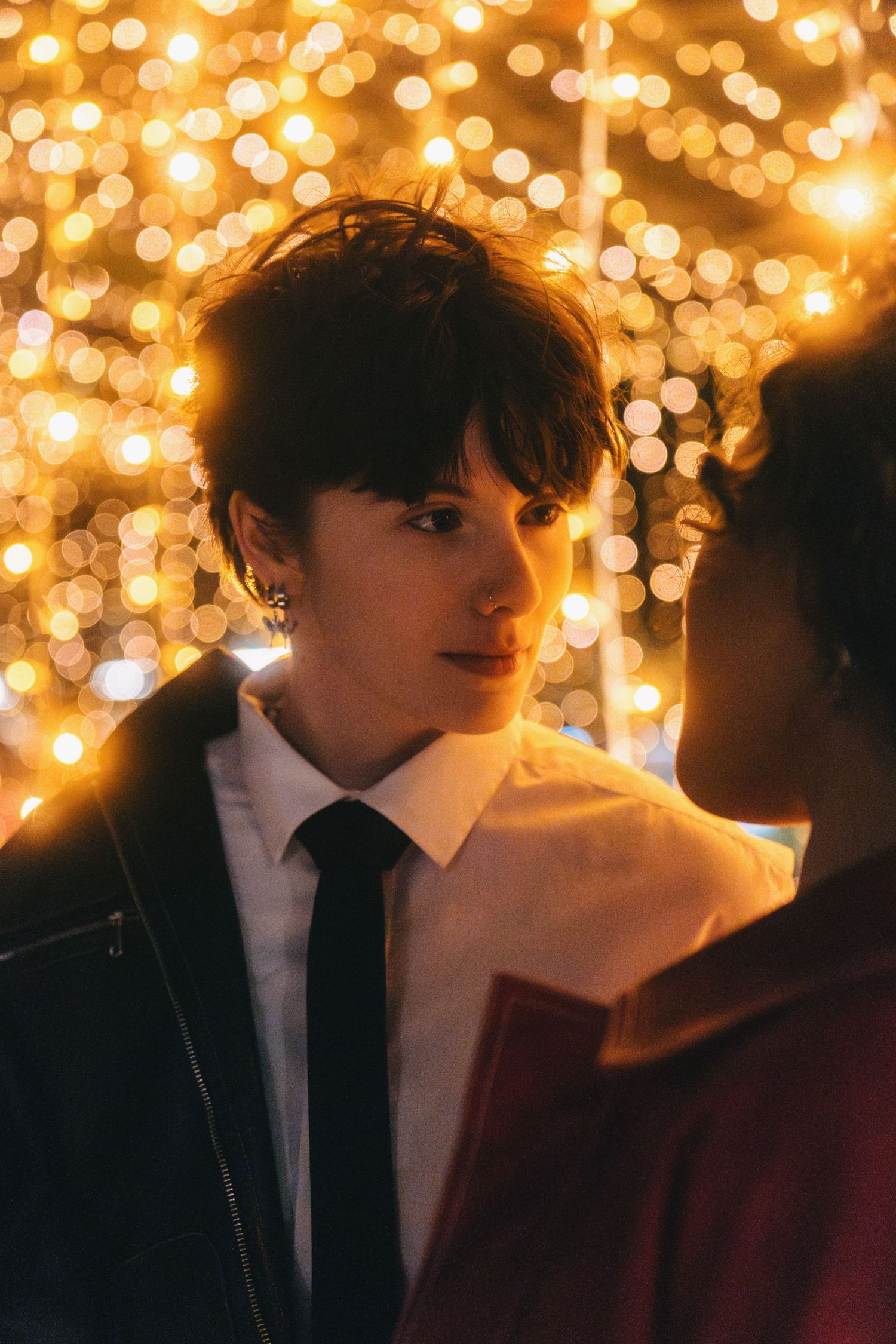 Couple in formal attire shares tender moment beneath sparkling overhead lights.
