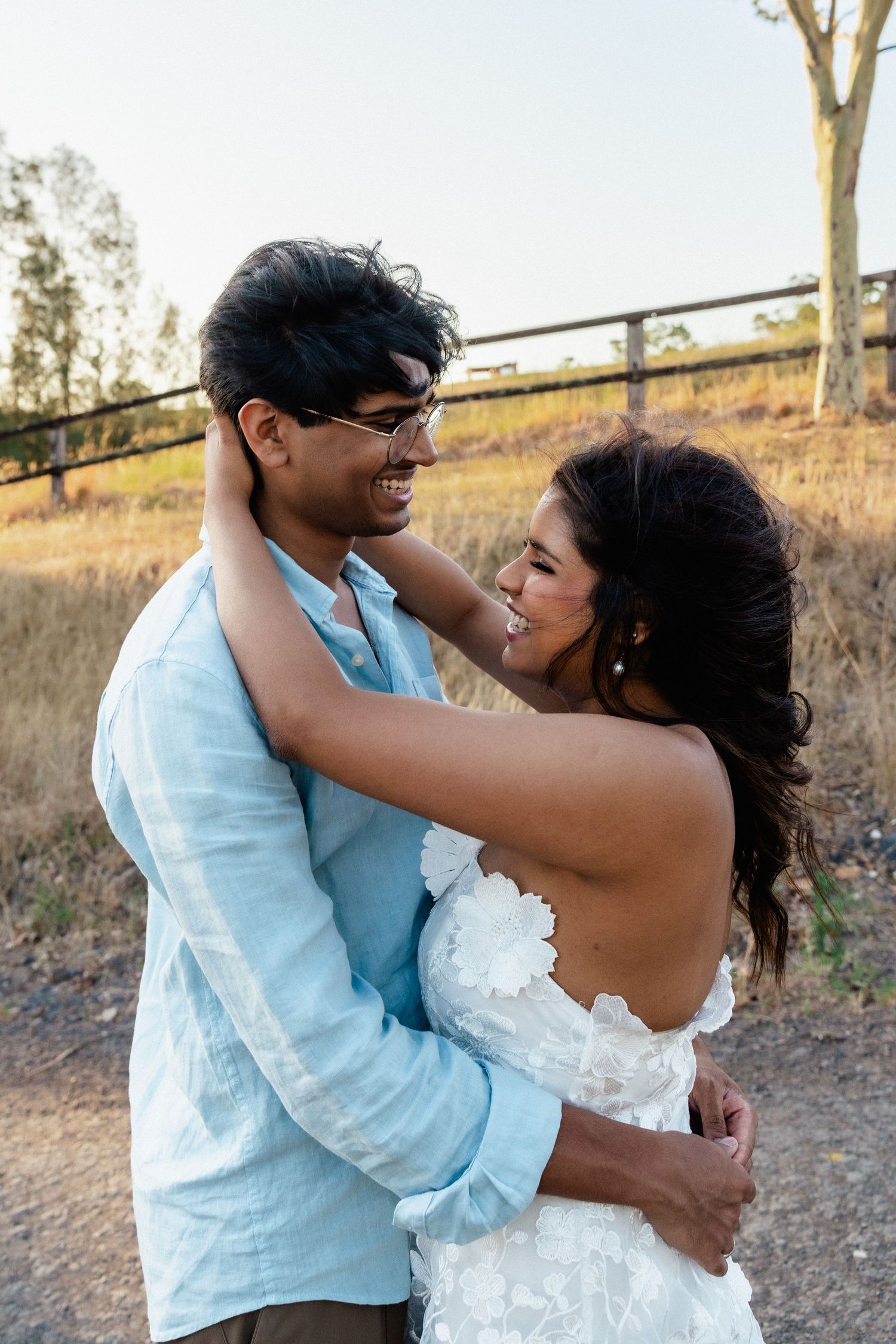 Romantic couple embracing and dancing in casual attire against a natural outdoor setting.