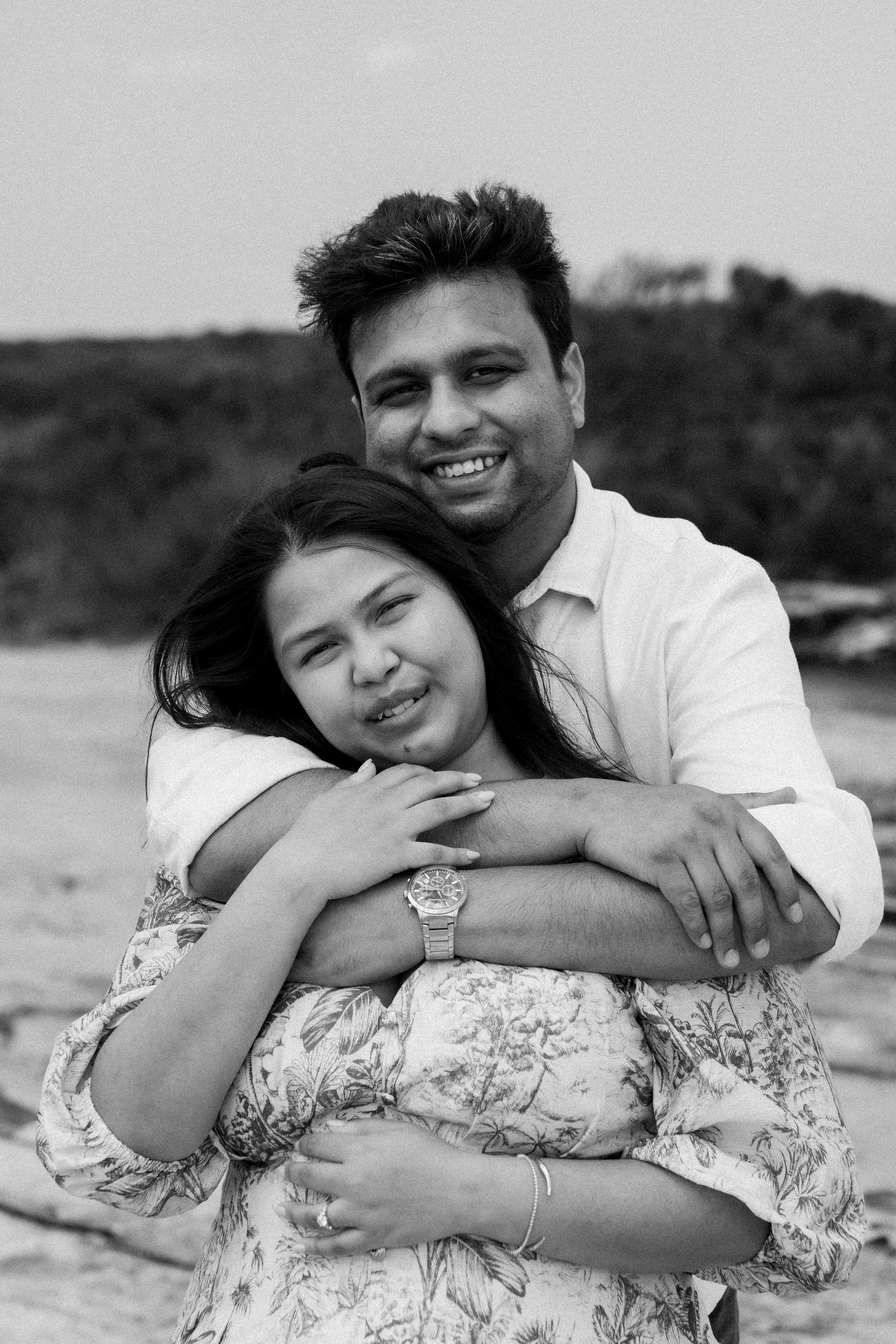 Black and white photos of a couple embracing and laughing together outdoors.