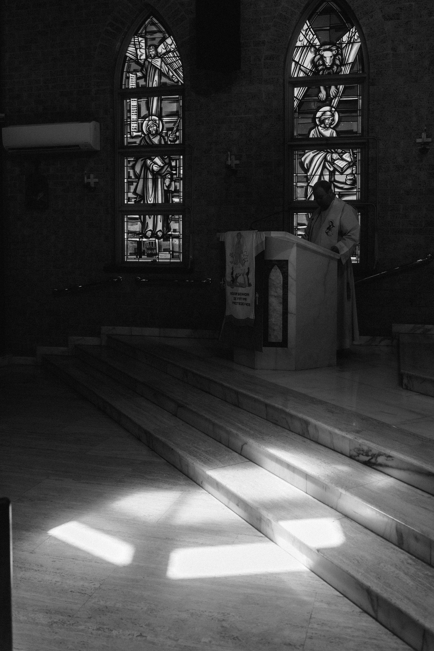 Sunlight streams through stained glass windows onto church floor in dramatic patterns.
