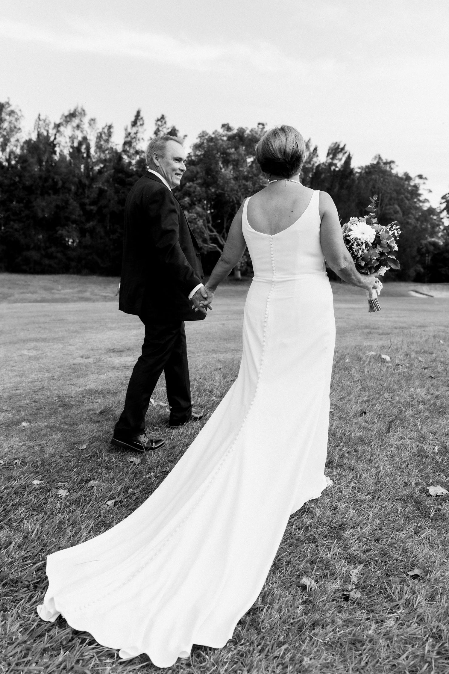 Flowing white wedding dress twirling in motion across a grassy outdoor setting.