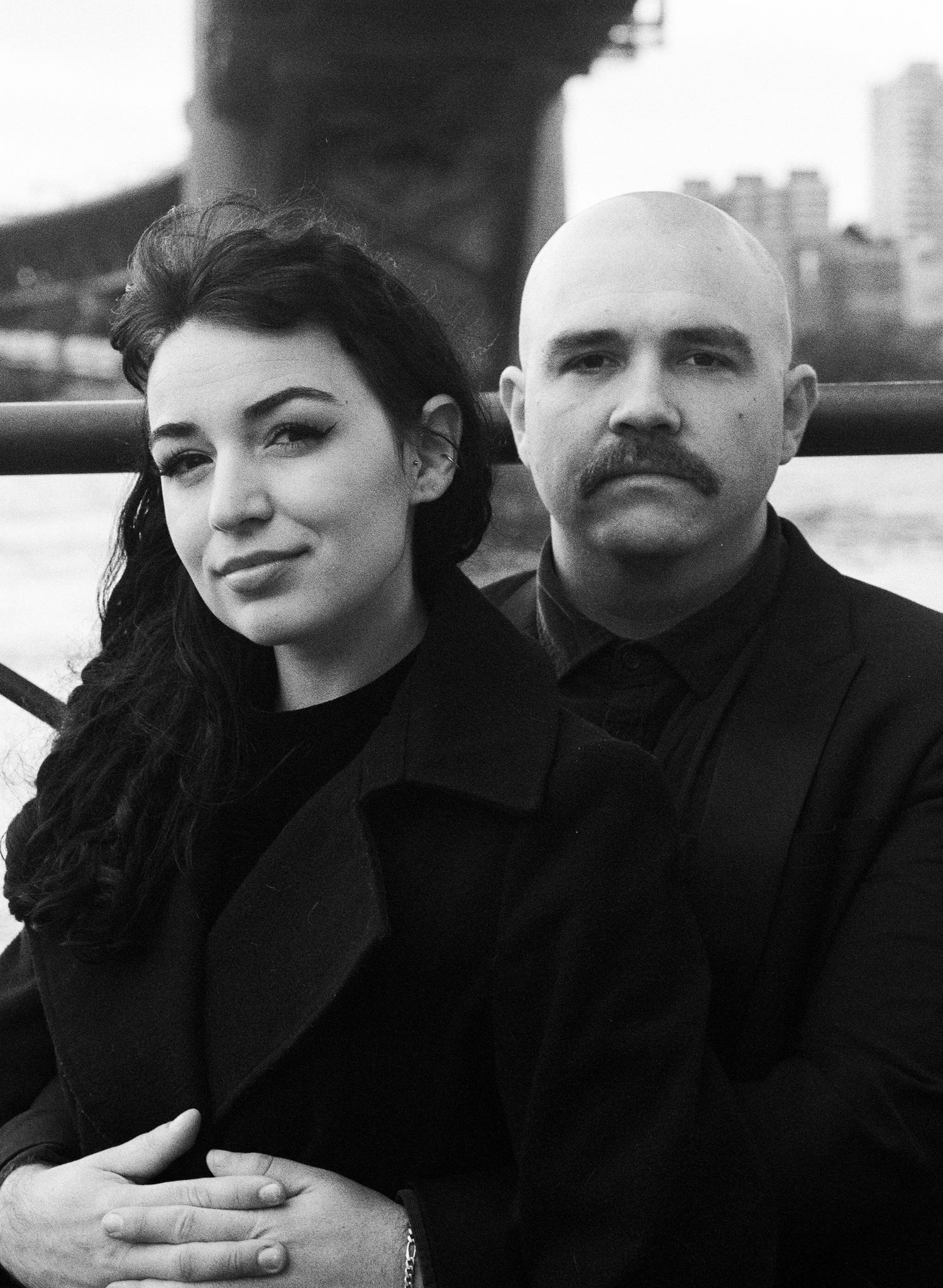 A couple in black clothing poses together for intimate portrait shots.