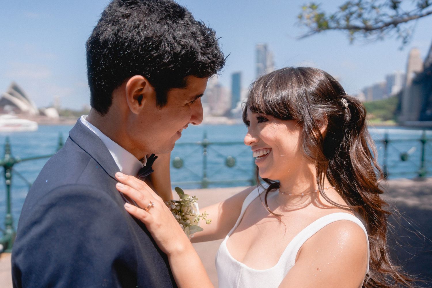 A couple shares an intimate moment by the waterfront with city views.