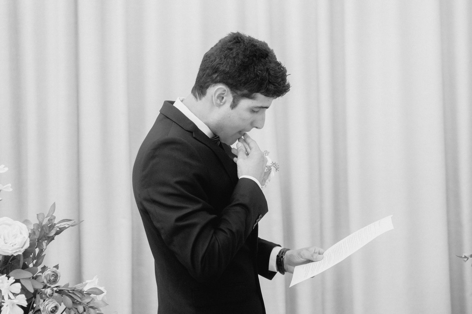 Wedding ceremony moment showing couple exchanging vows in front of sage green curtains.