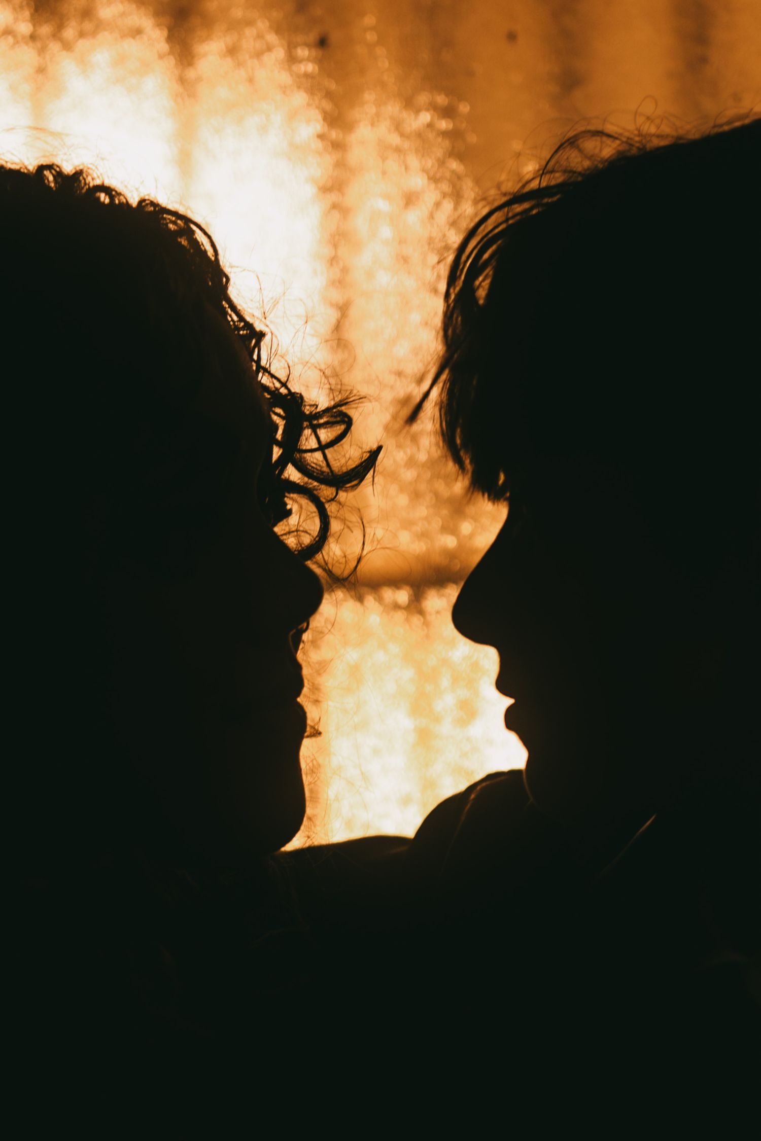 Silhouettes of two people against a golden bokeh background.