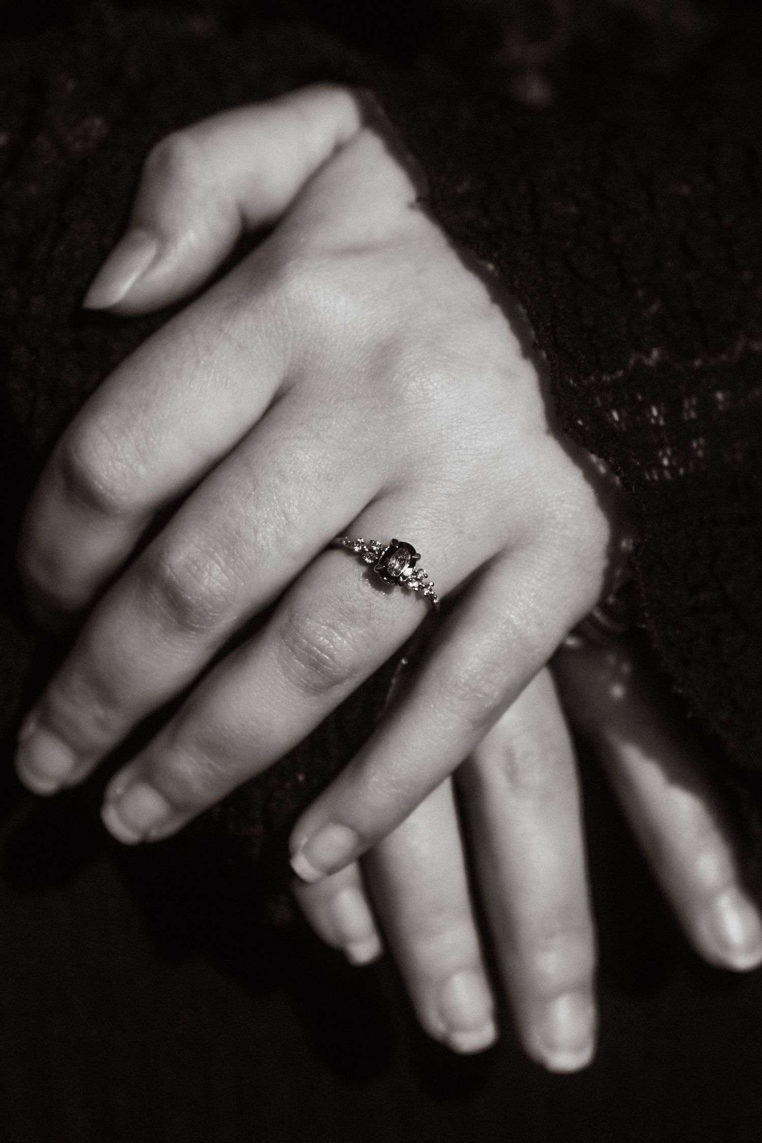 Close-up black and white photo of hands with an engagement ring.