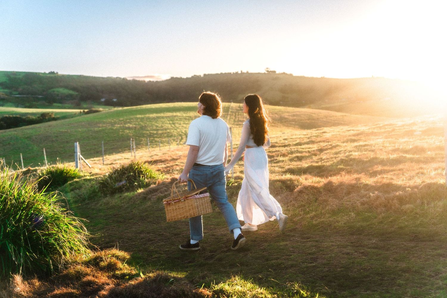 Silhouetted couple walking together against a golden sunset landscape.