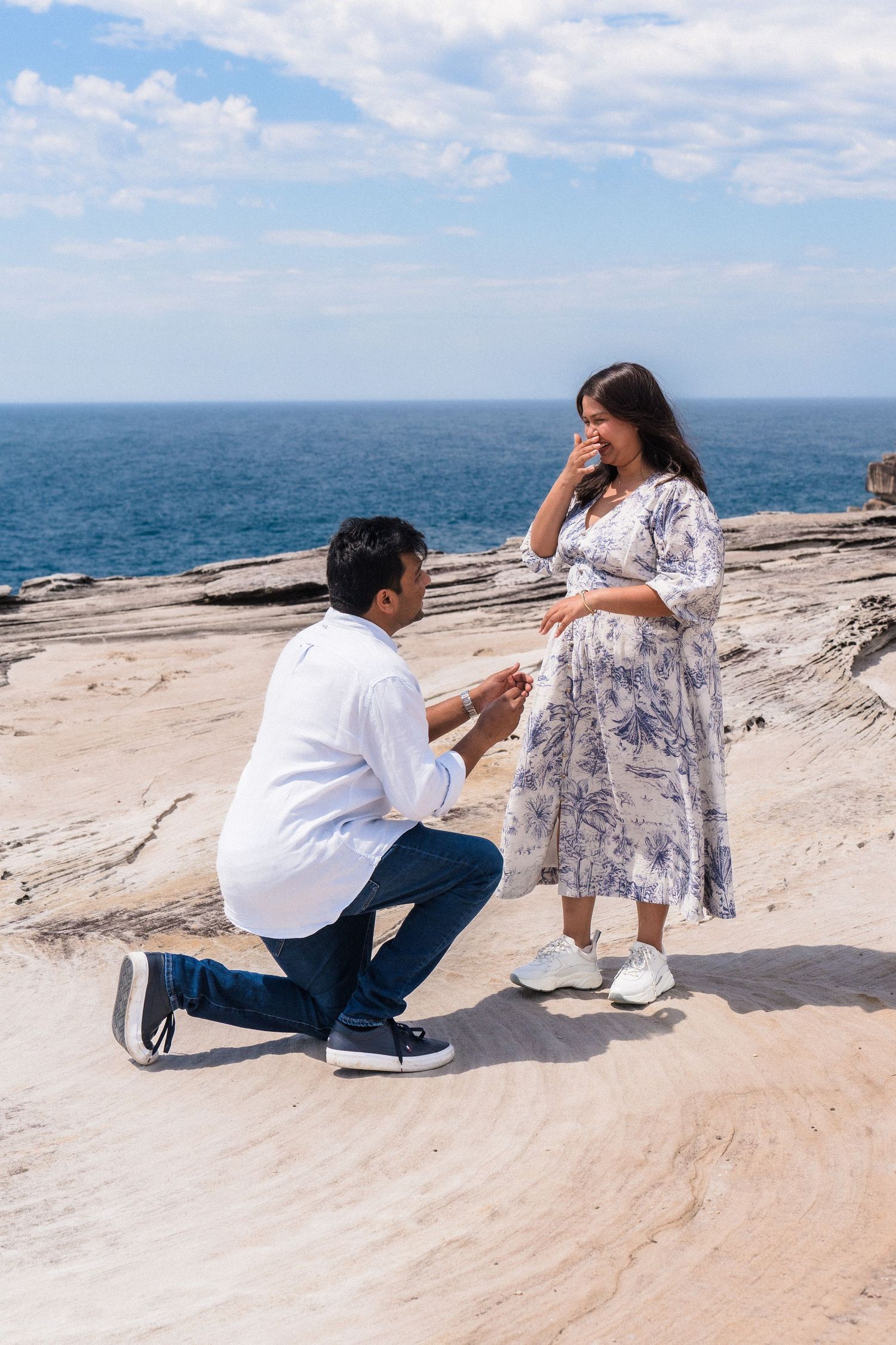 A seaside proposal sequence with rocky cliffs and ocean views in the background.