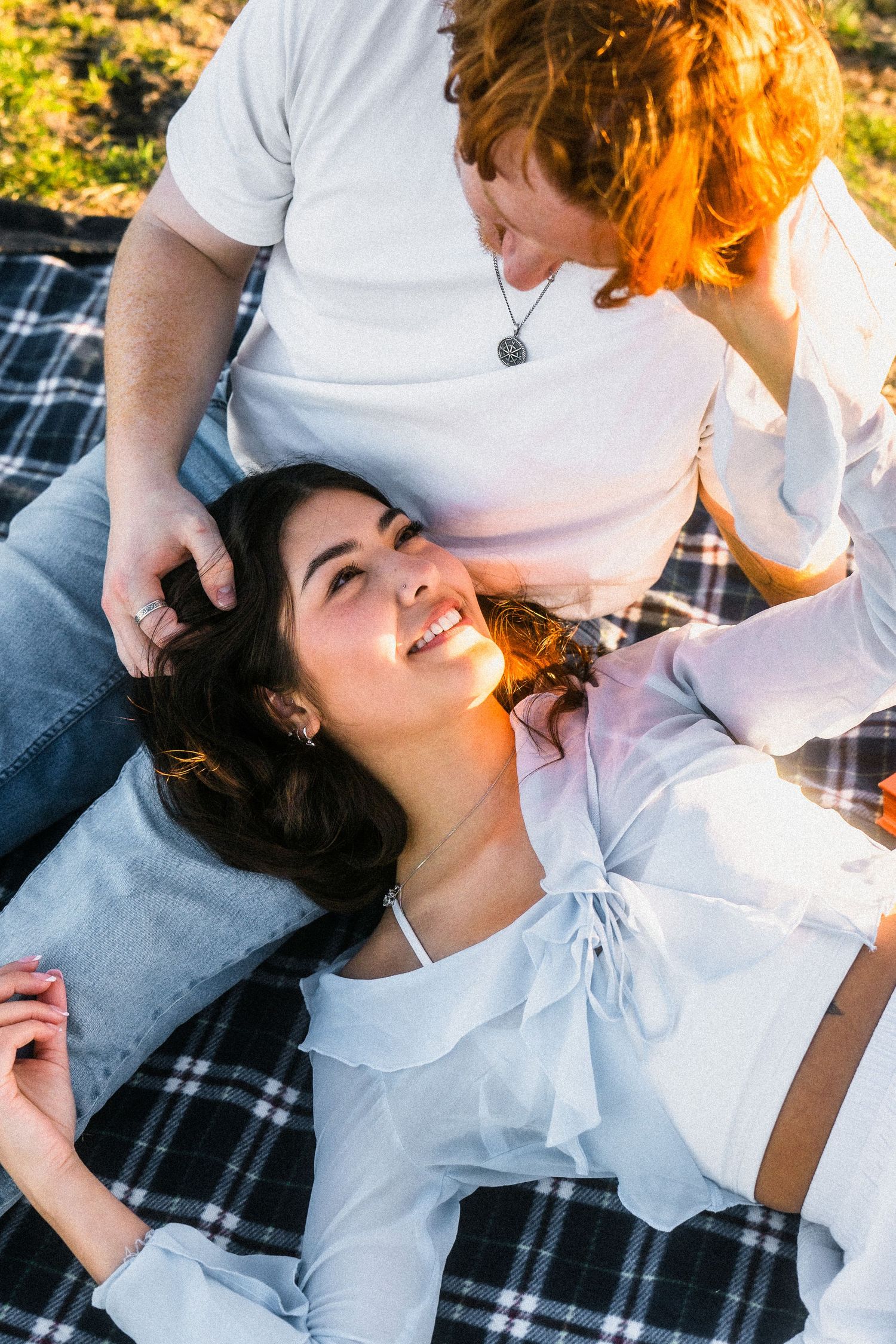 Romantic couple photos on a plaid blanket with warm sunset lighting.