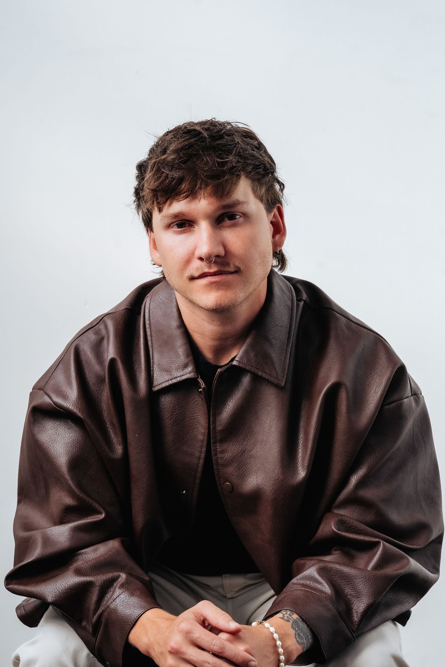 Studio portrait series of a person wearing an oversized brown leather jacket.