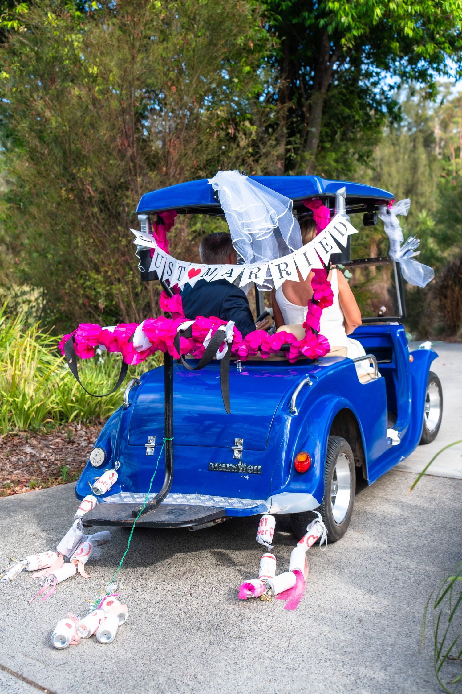 Vintage blue car decorated with wedding flowers and 'Just Married' banner.
