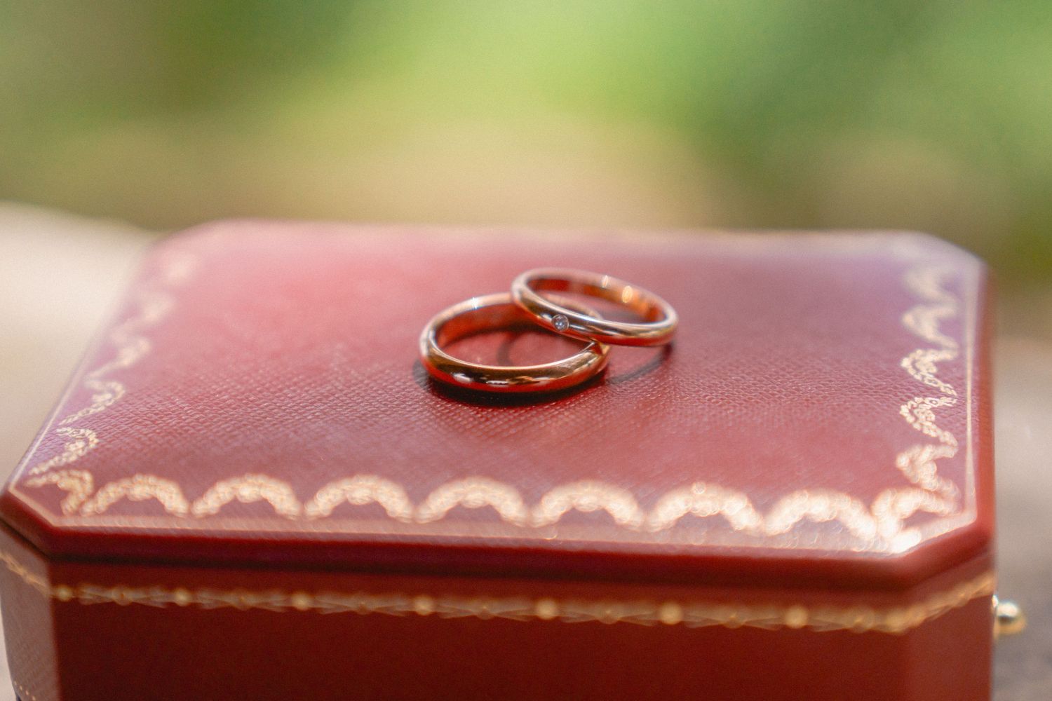 Close-up of wedding rings on a pink leather surface.