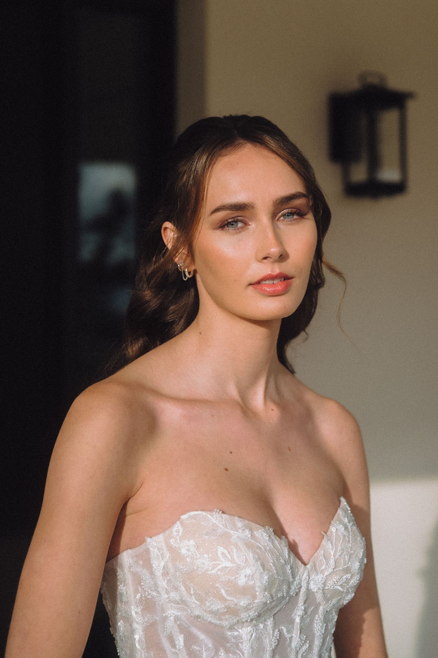 Dramatic indoor bridal portrait highlighting detailed corset bodice and soft makeup.
