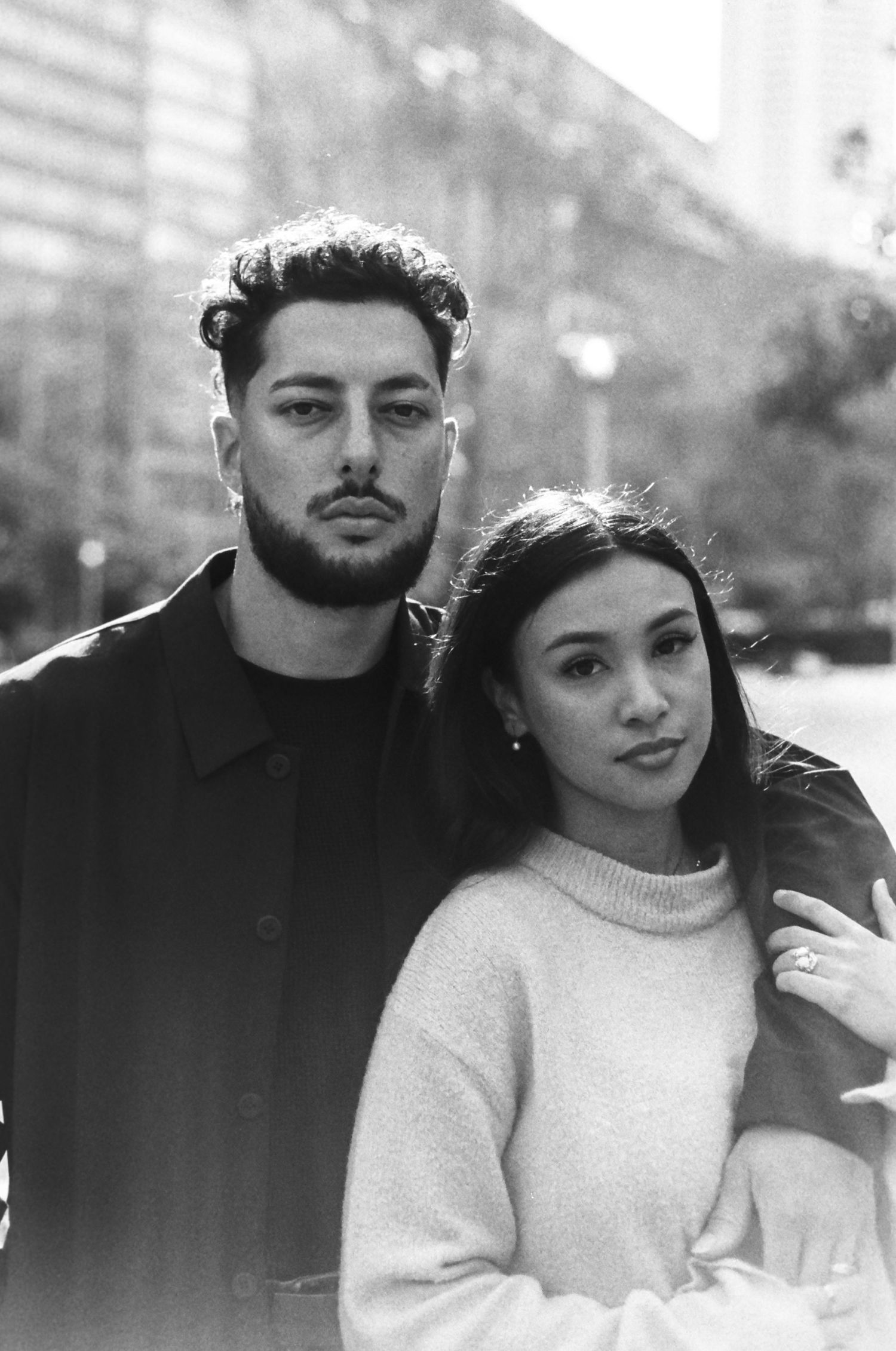 A stylish couple poses for a portrait in an urban setting.