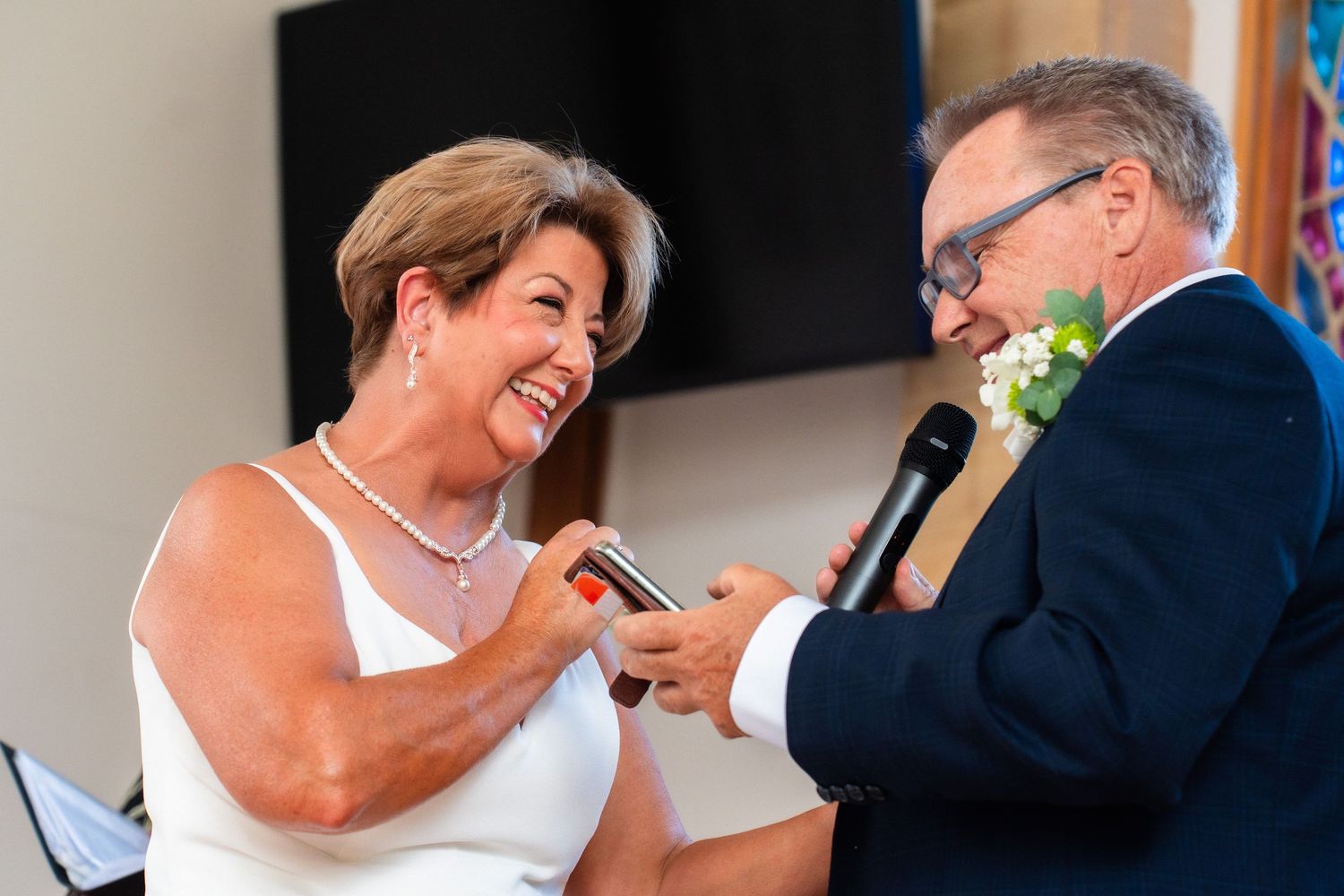 Two people sharing a joyful moment while speaking into microphones at a celebration.