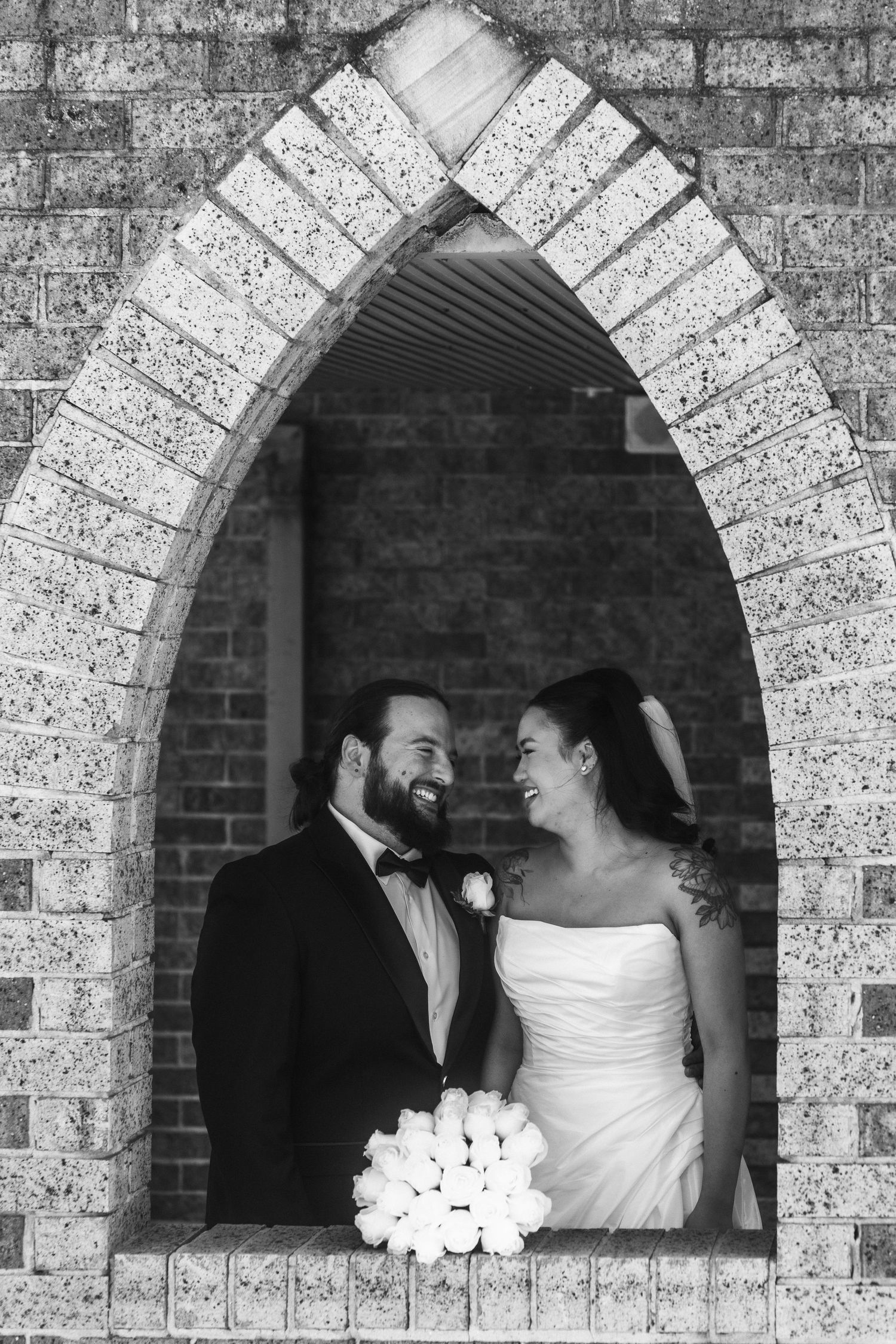 A series of black and white wedding photos showing a couple framed within stone archways.
