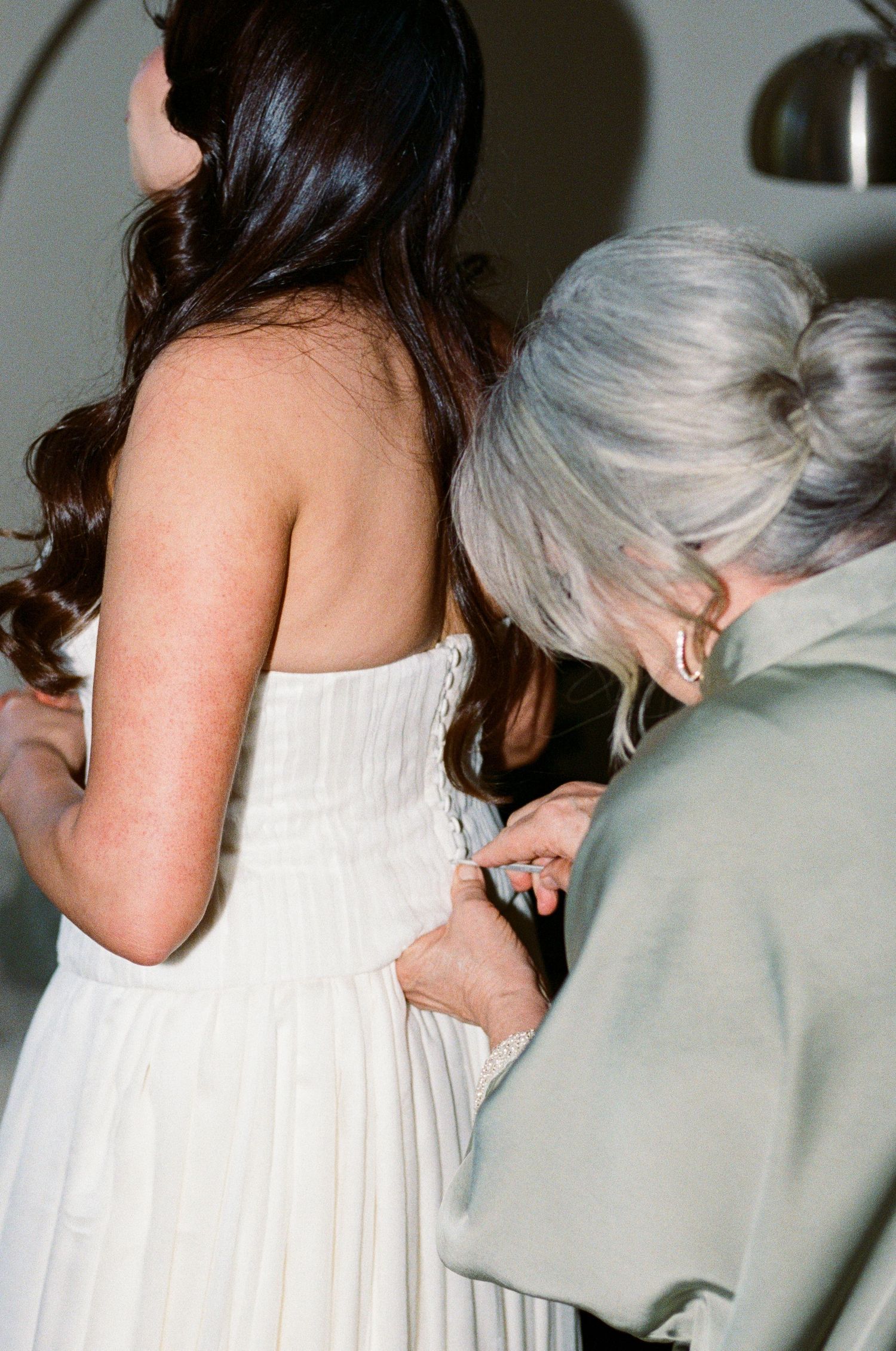 Wedding dress being adjusted and fitted in an intimate pre-ceremony moment.
