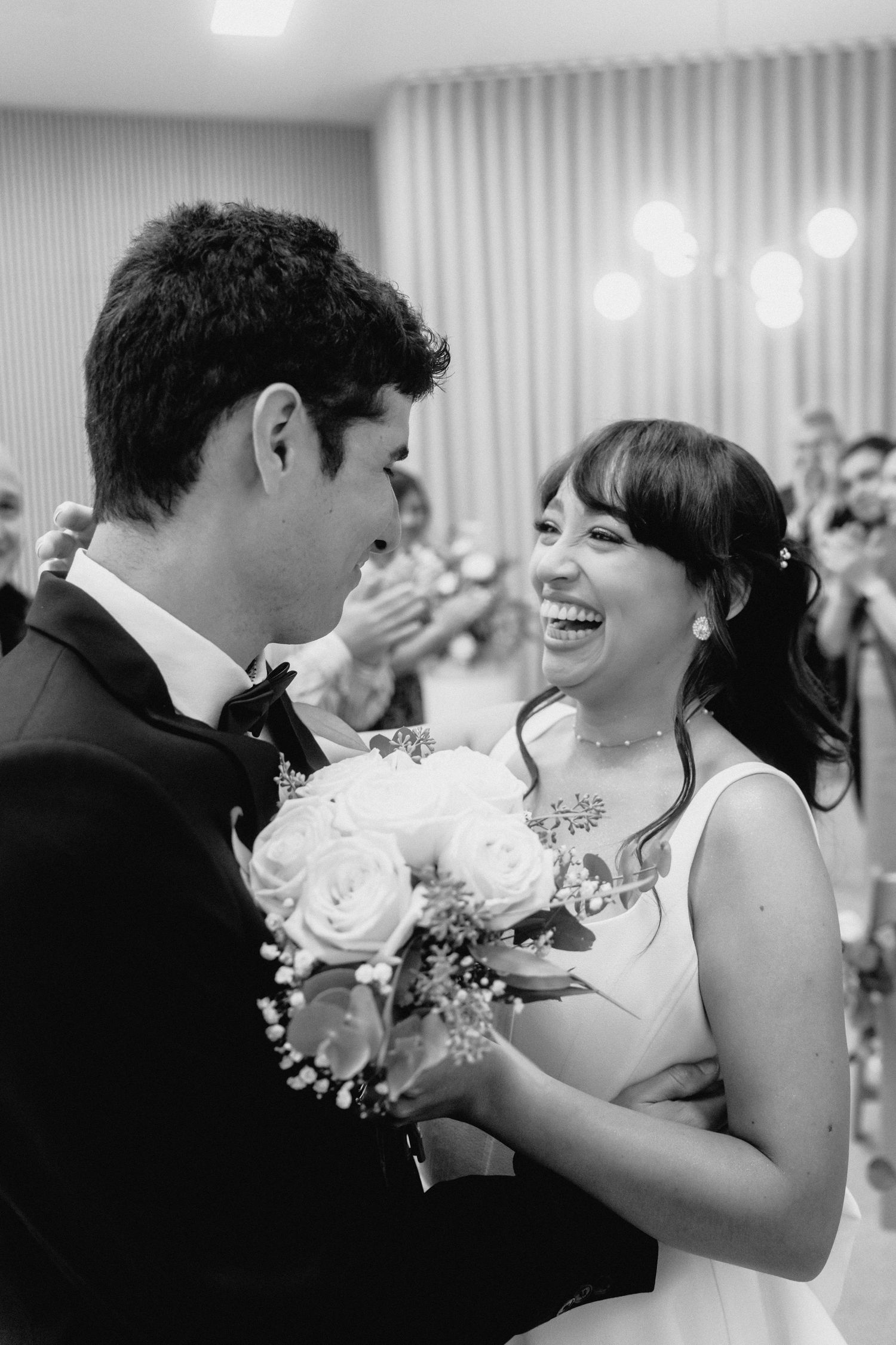 A couple shares joyful laughter during a romantic dance at their wedding reception.