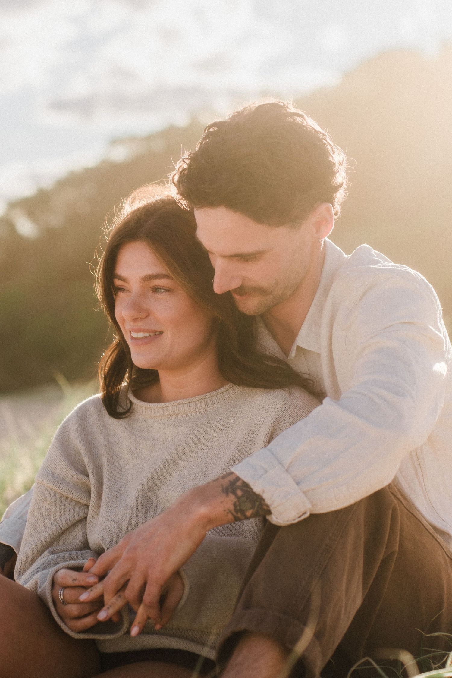 Intimate couple sharing tender moments in warm sunlight while wearing casual sweaters.