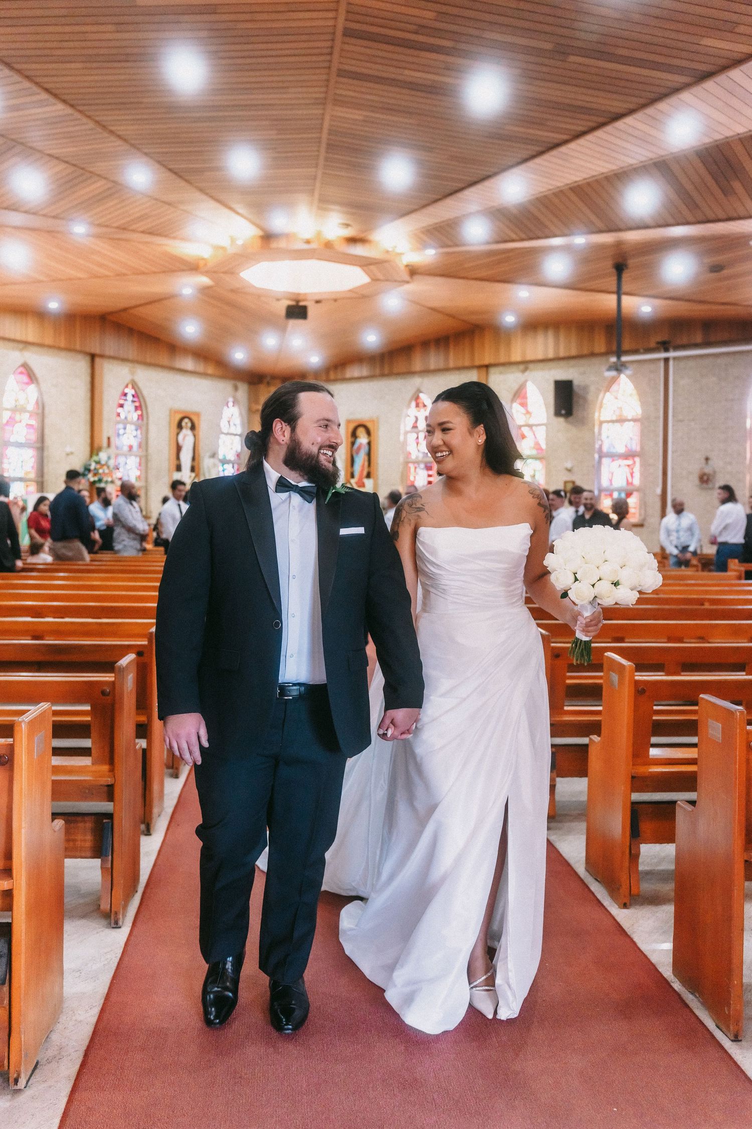 Church sanctuary with wooden pews and ceiling during wedding celebration.