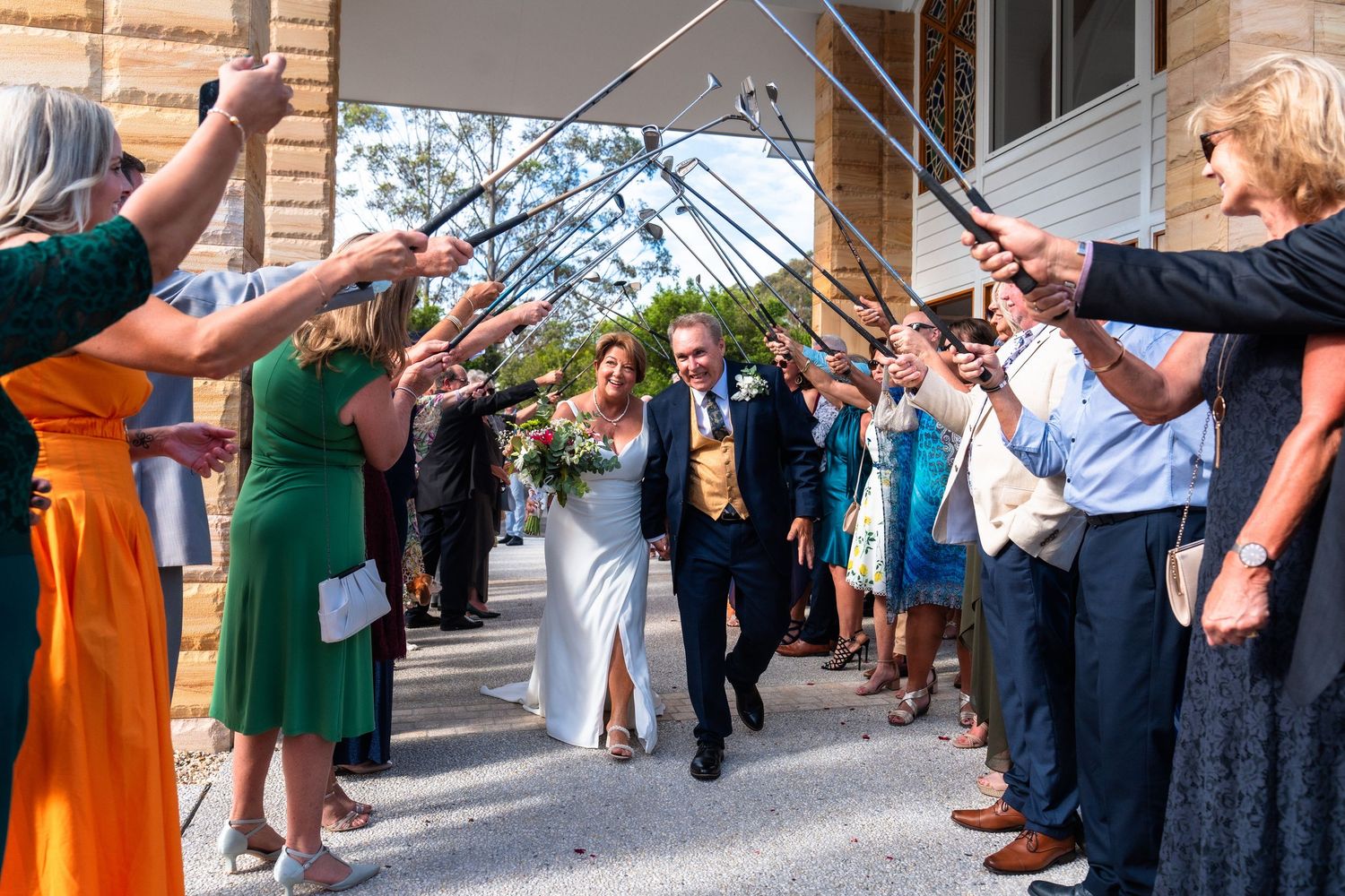 Wedding guests forming a tunnel with raised arms for the newlyweds to walk through.
