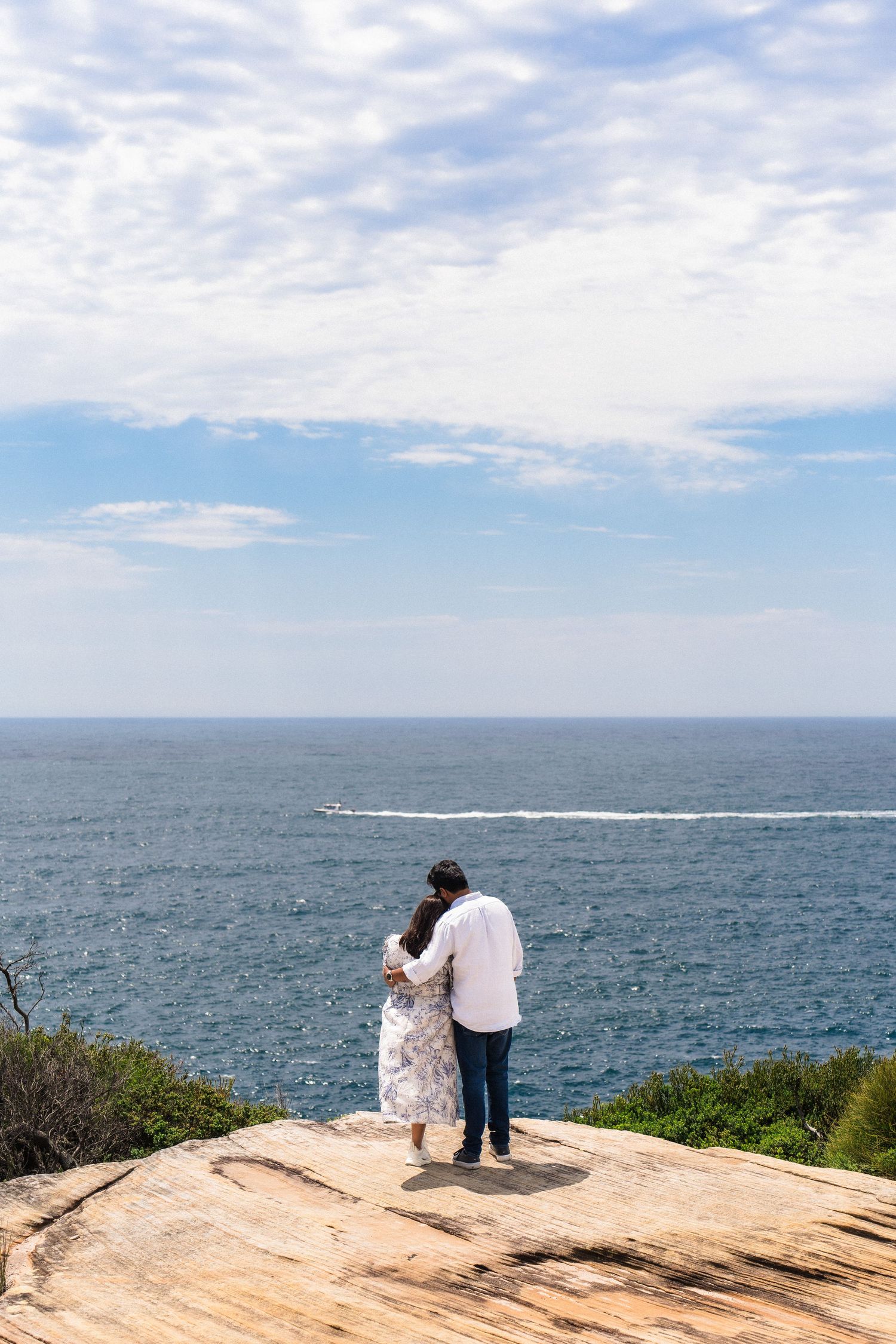 Couple stands together overlooking dramatic ocean views from coastal cliffs.