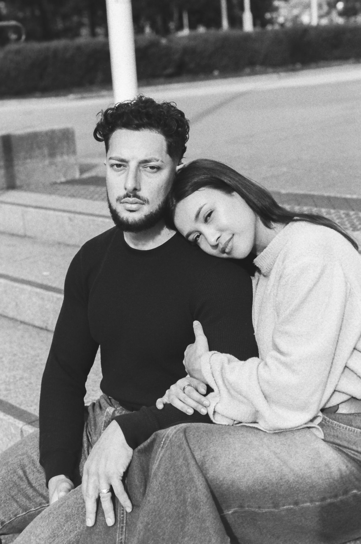 A couple relaxes together on outdoor steps in casual black and white sweaters.