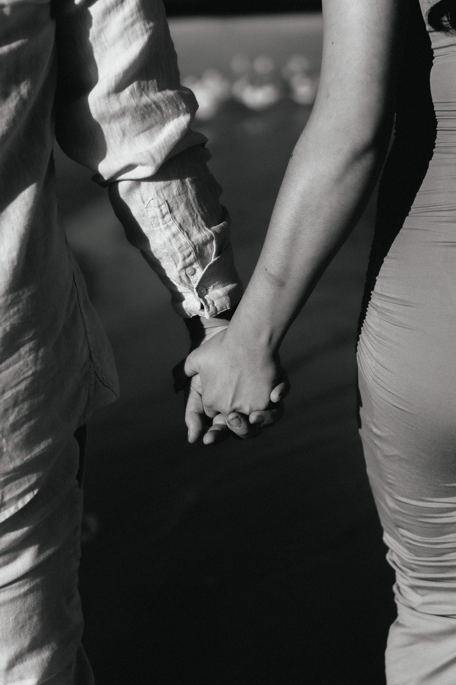 Close-up black and white shot of two people holding hands.