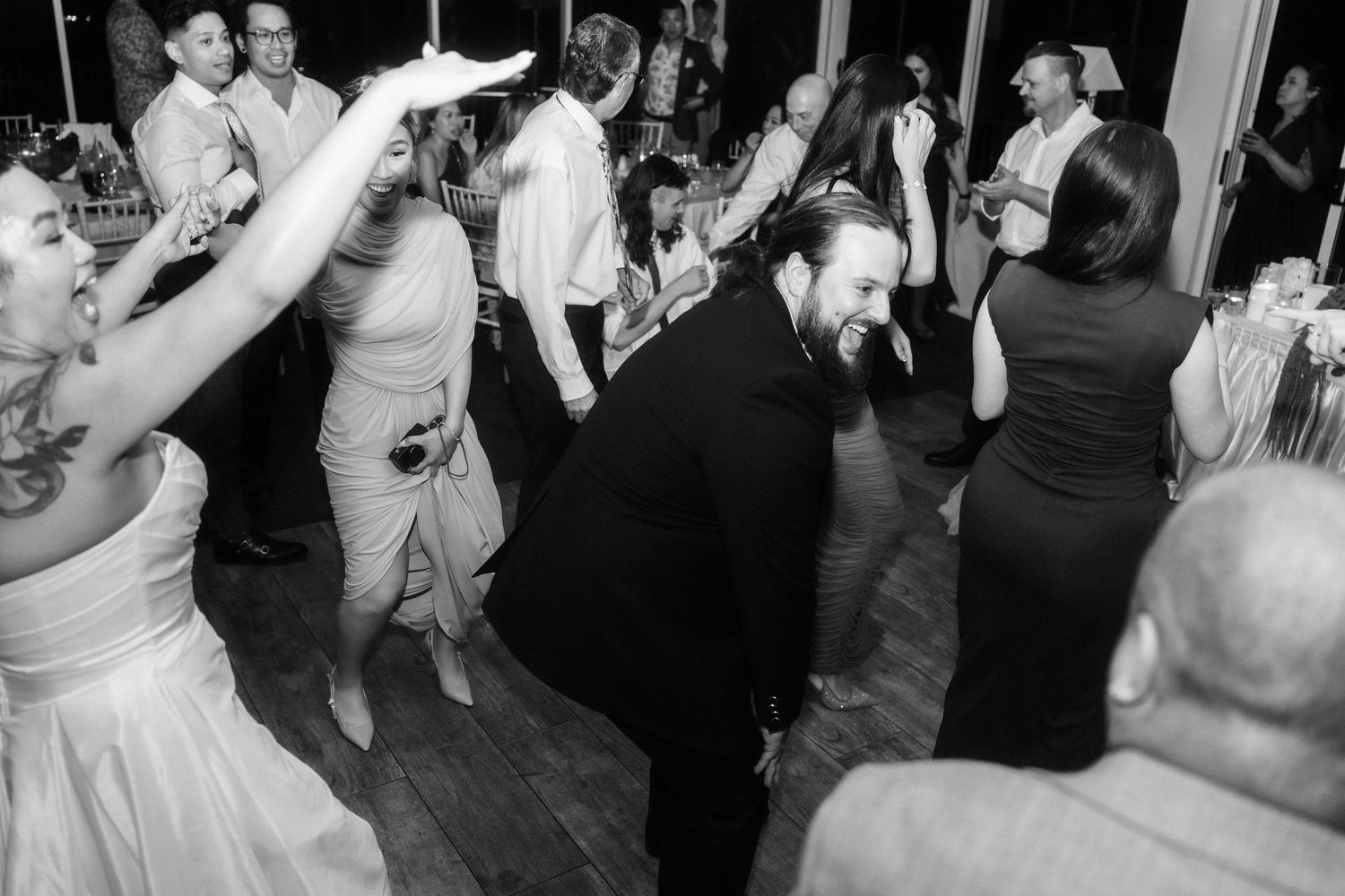 Black and white photo of wedding guests dancing and celebrating.