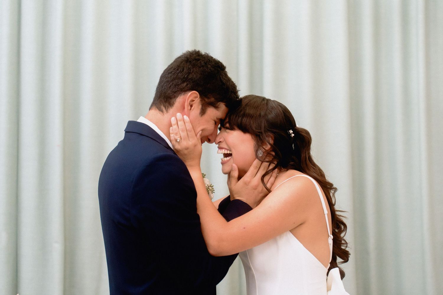 Wedding couple embracing in elegant venue with modern decor and soft lighting.