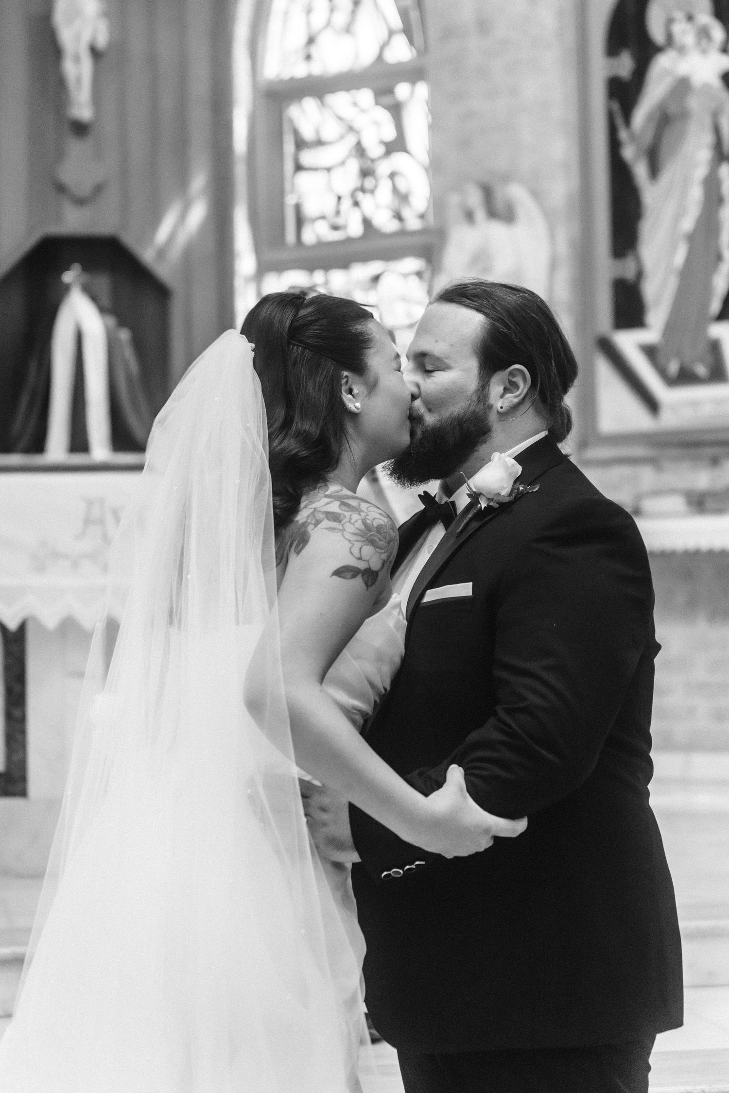 Intimate wedding moment captured in front of church stained glass windows.