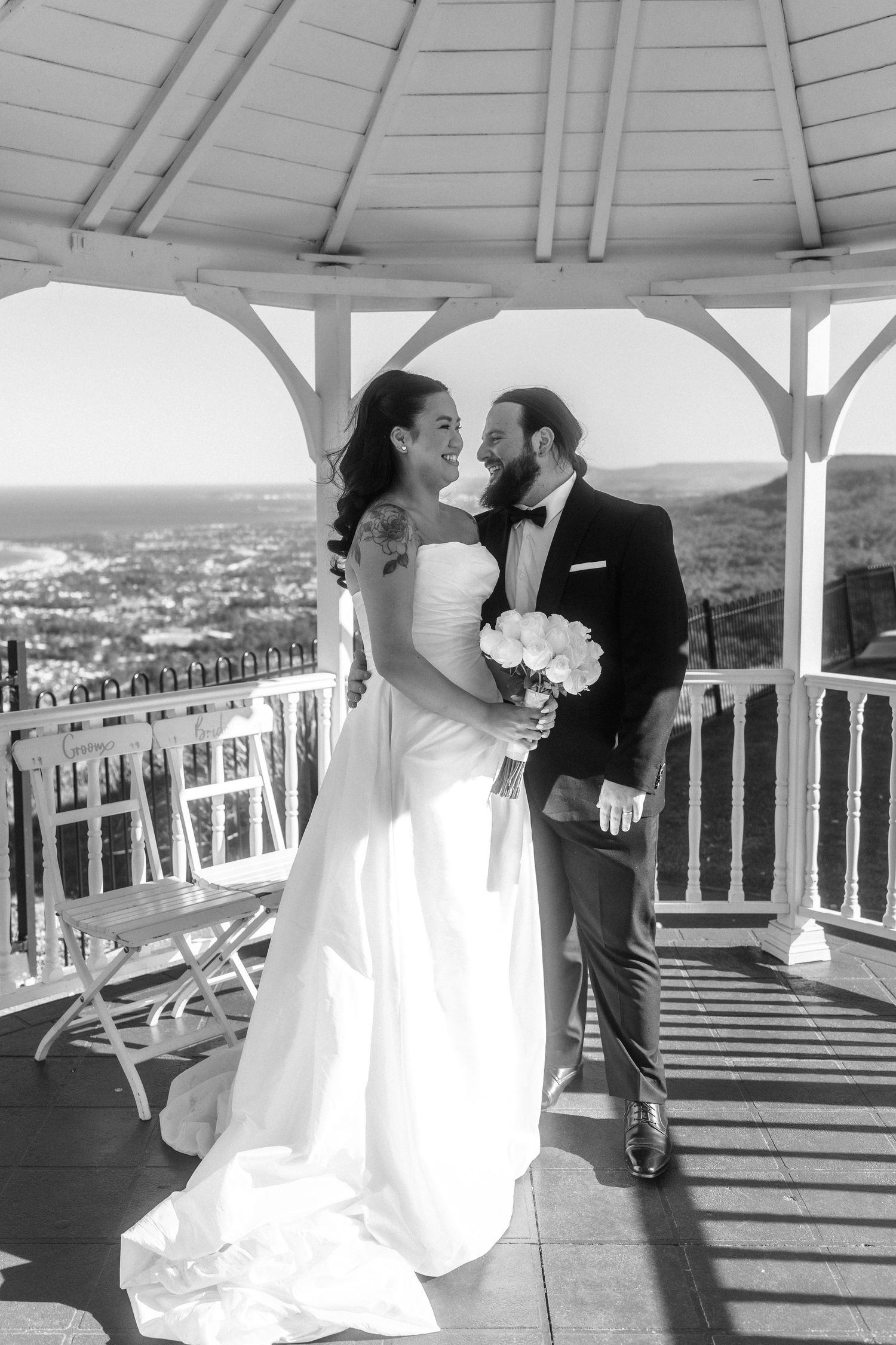 Wedding couple sharing romantic moments on a scenic balcony overlooking city views.