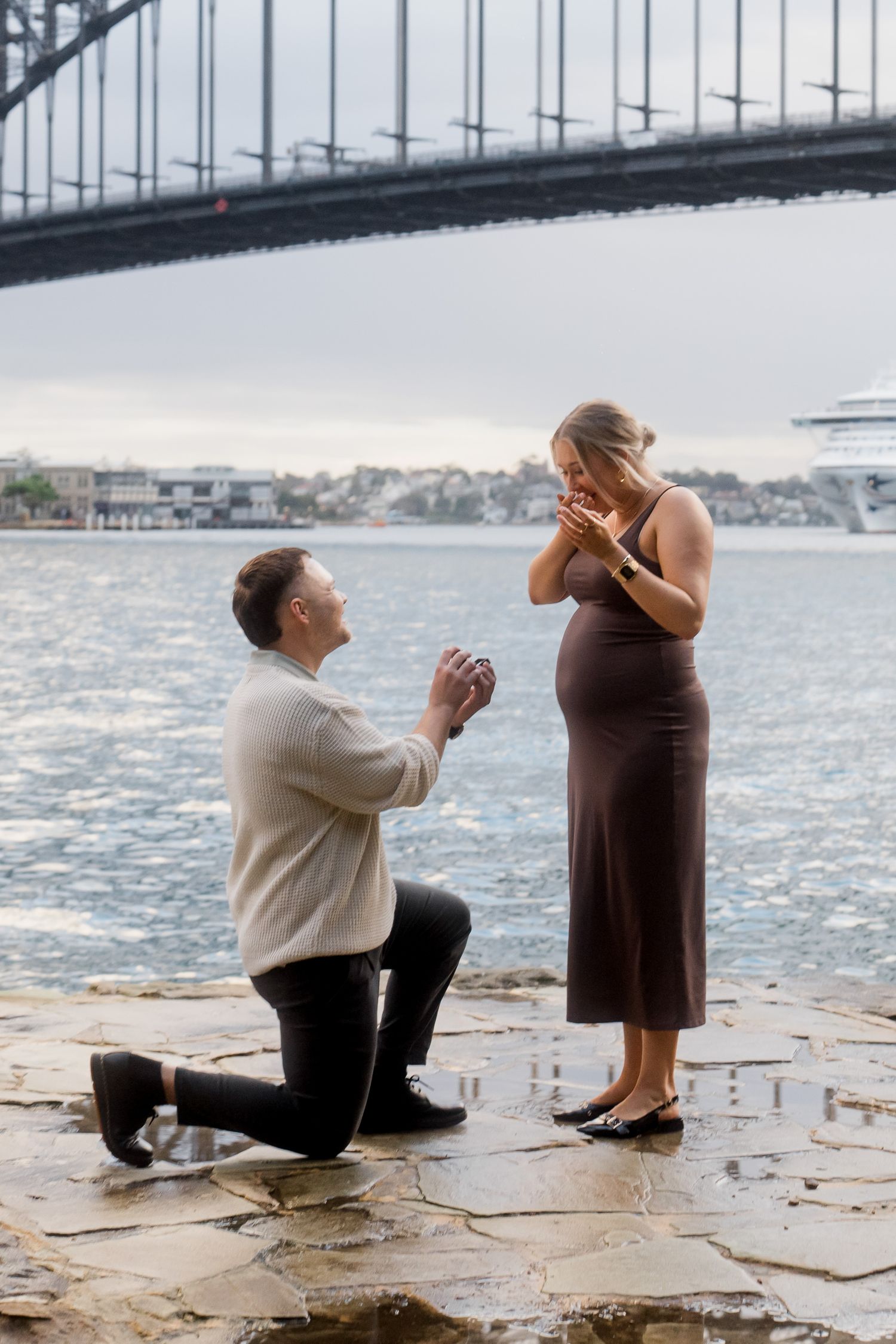 A marriage proposal sequence by the waterfront with a bridge in the background.
