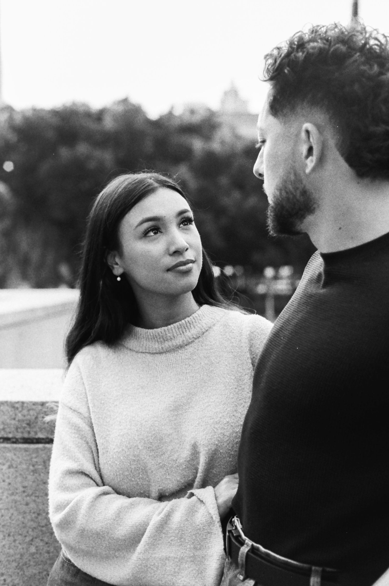 A couple shares an intimate moment while having a conversation outdoors.