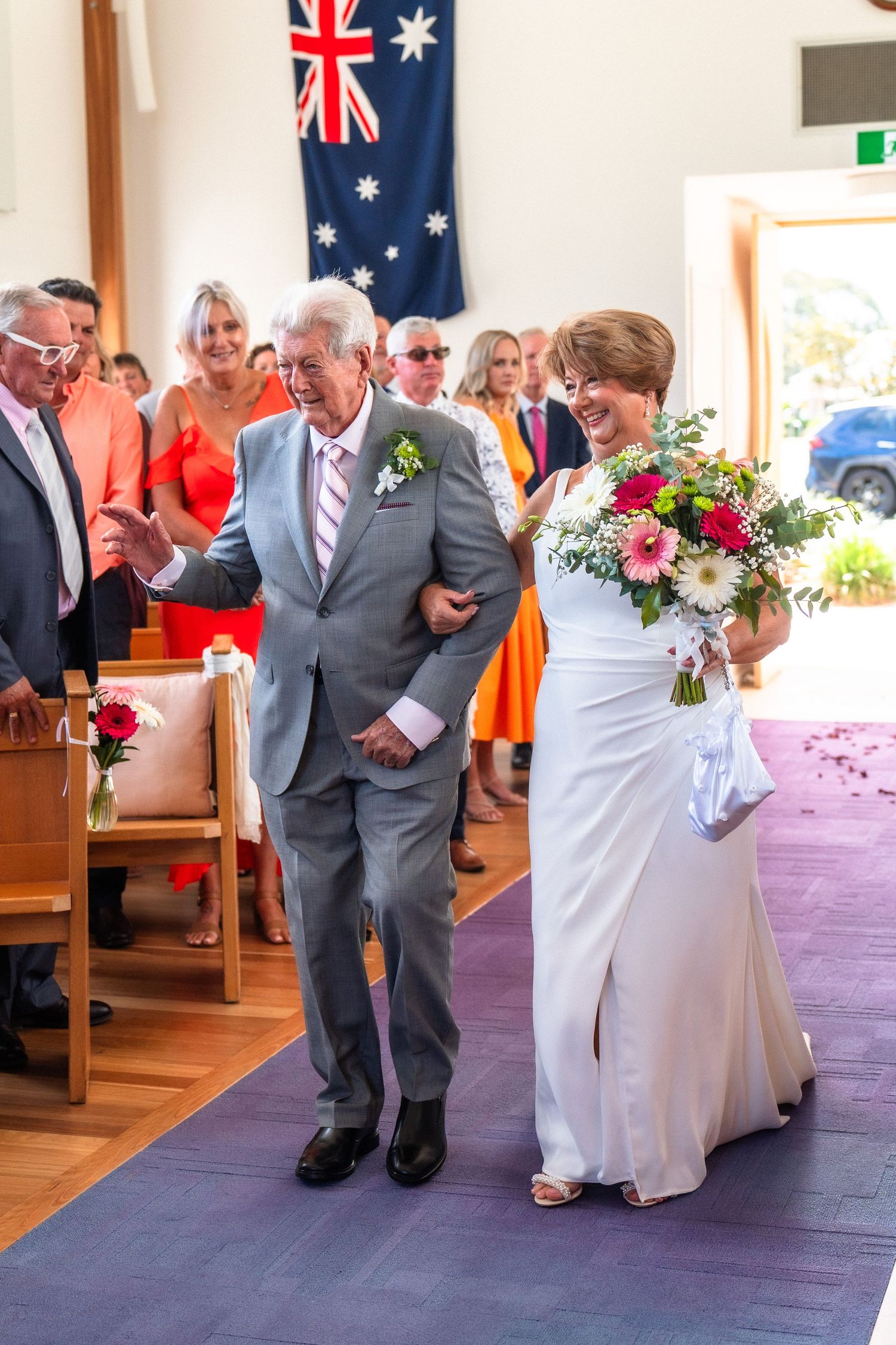 Wedding ceremony in church with Australian flags and purple aisle runner.