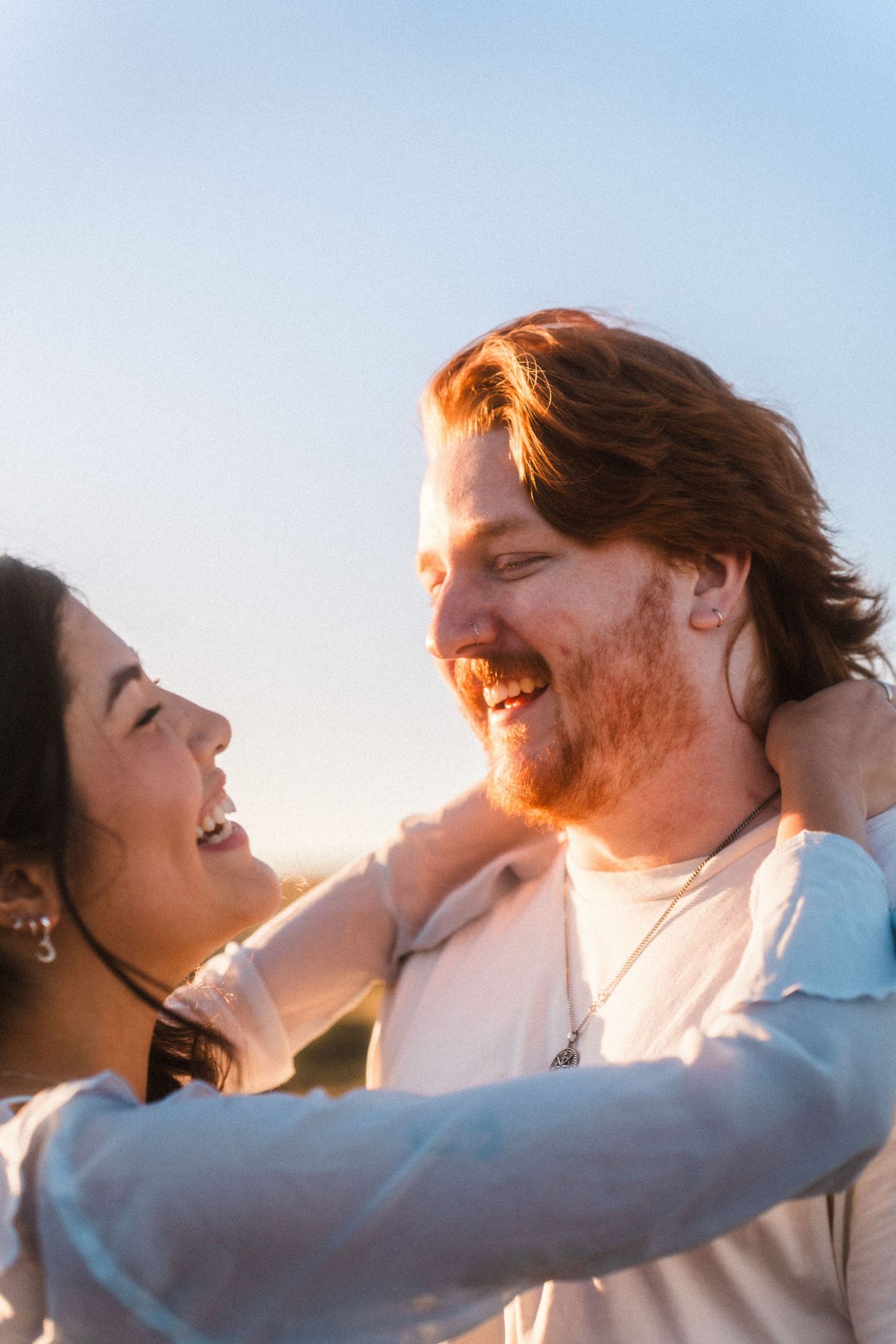 A couple embraces in warm sunlight at golden hour.