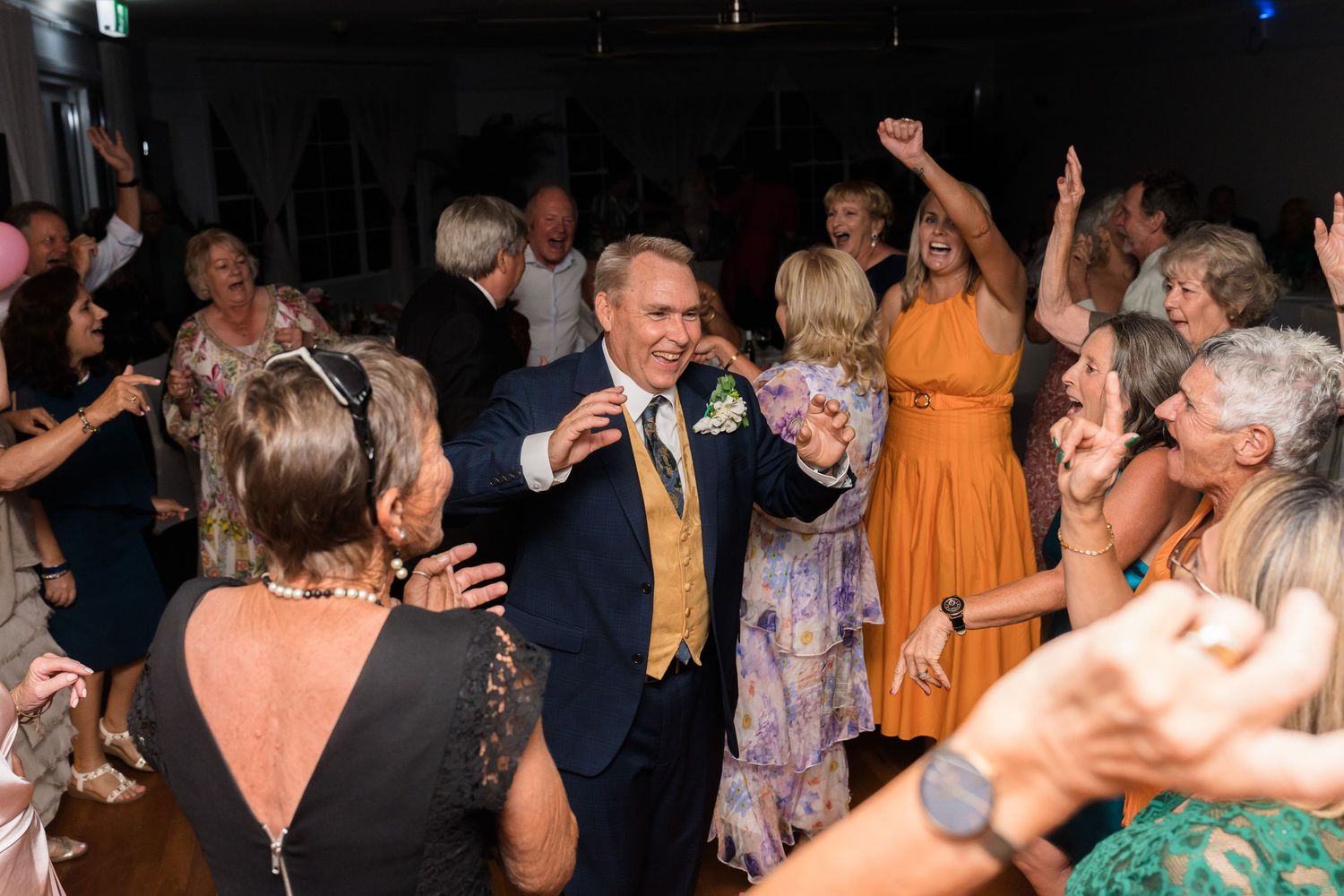Energetic wedding reception scene with dancers celebrating on a crowded dance floor.