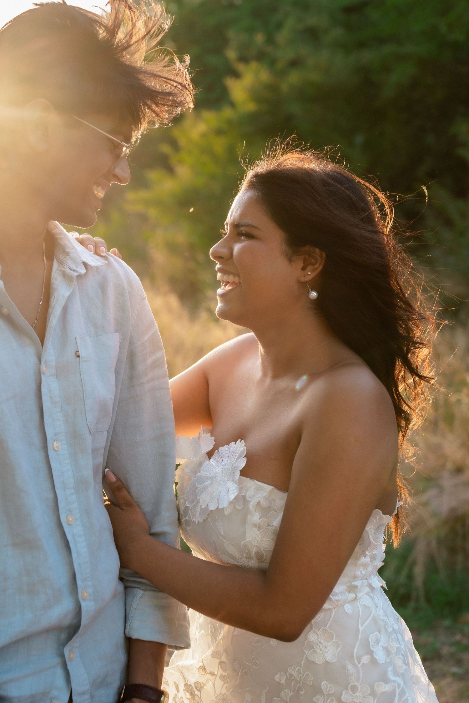 A romantic sunset photoshoot featuring a couple in white attire sharing joyful moments together.