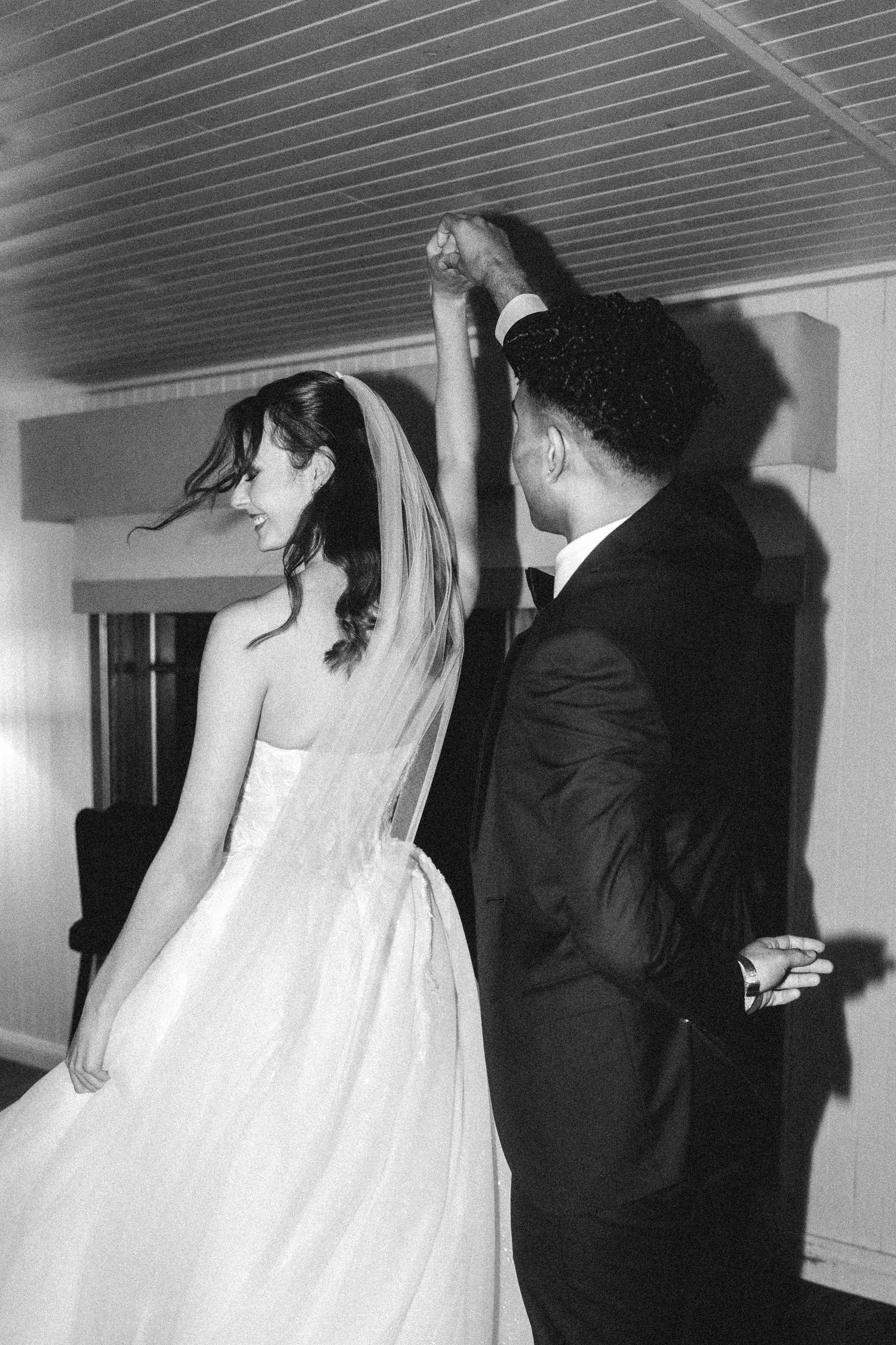 A couple in wedding attire shares an intimate dance in a dimly lit indoor space.