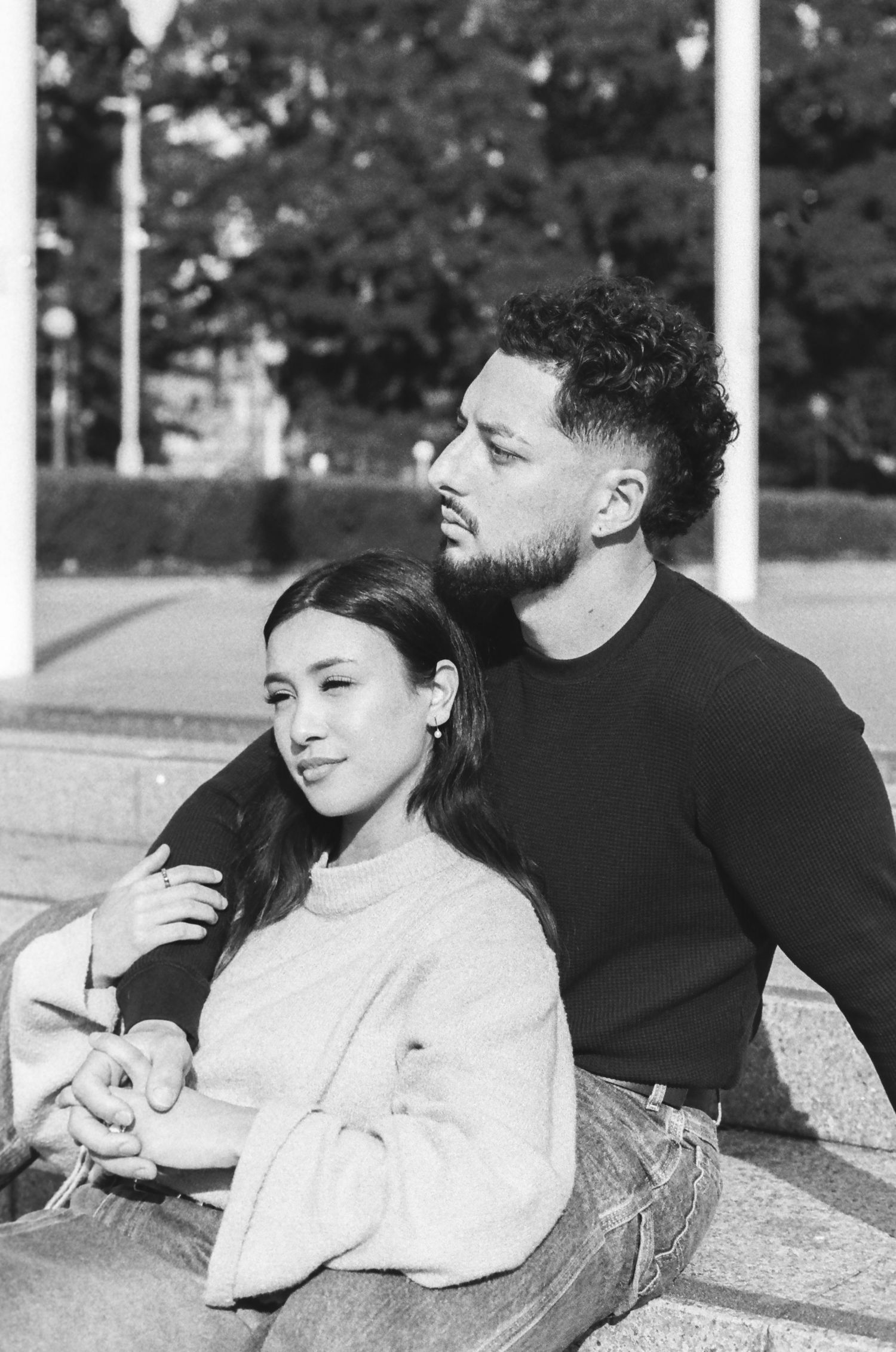 A couple relaxes together on concrete steps in contrasting black and white sweaters.