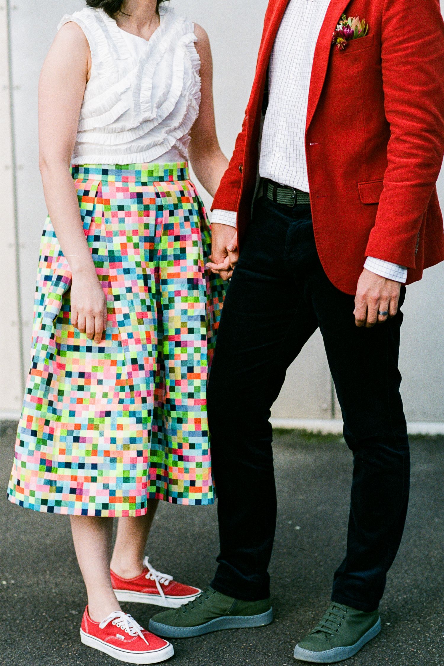 Detail shot of colorful pixel print skirt paired with red blazer and casual sneakers.