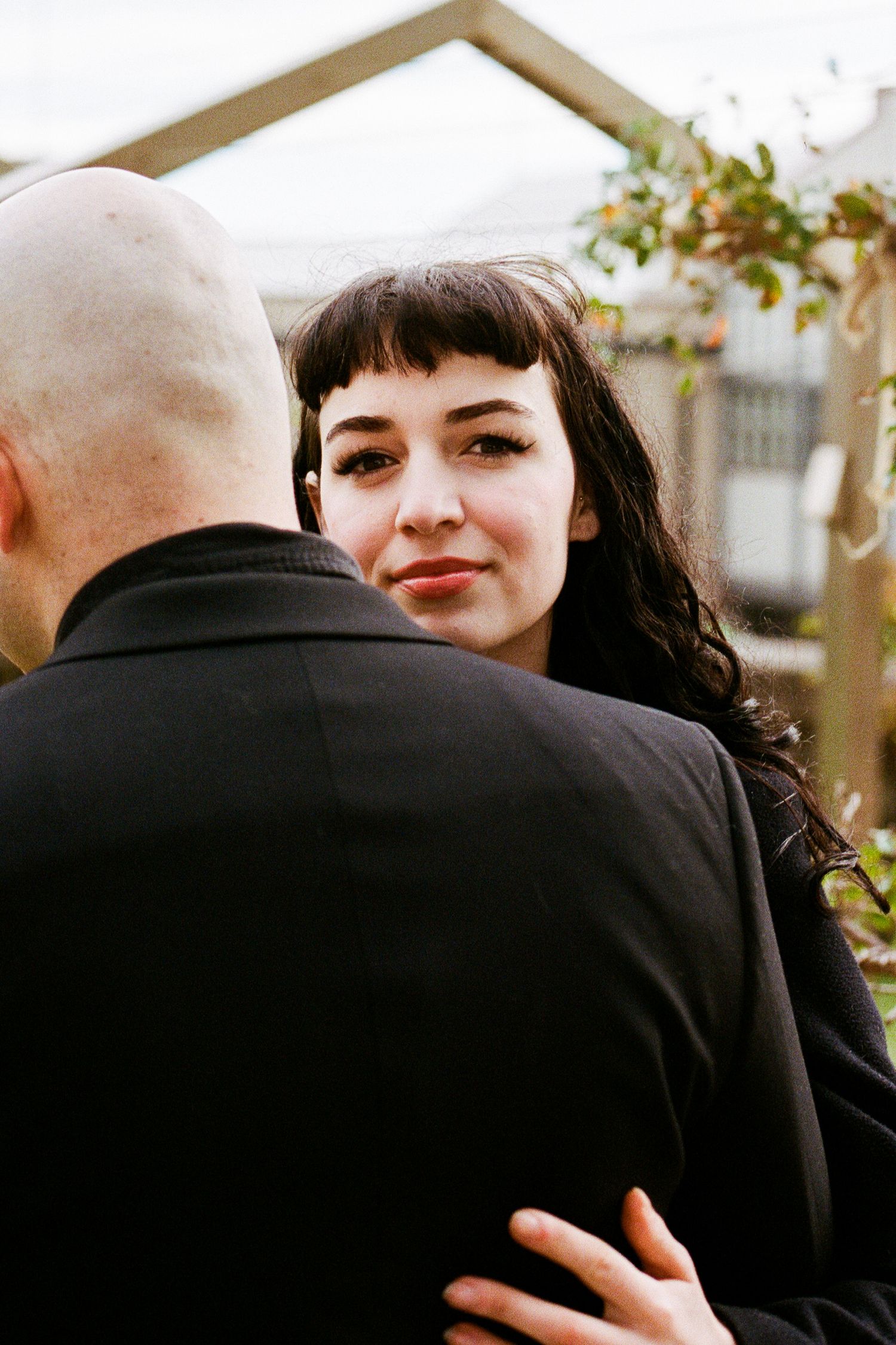 Two people in black share an intimate moment outdoors.