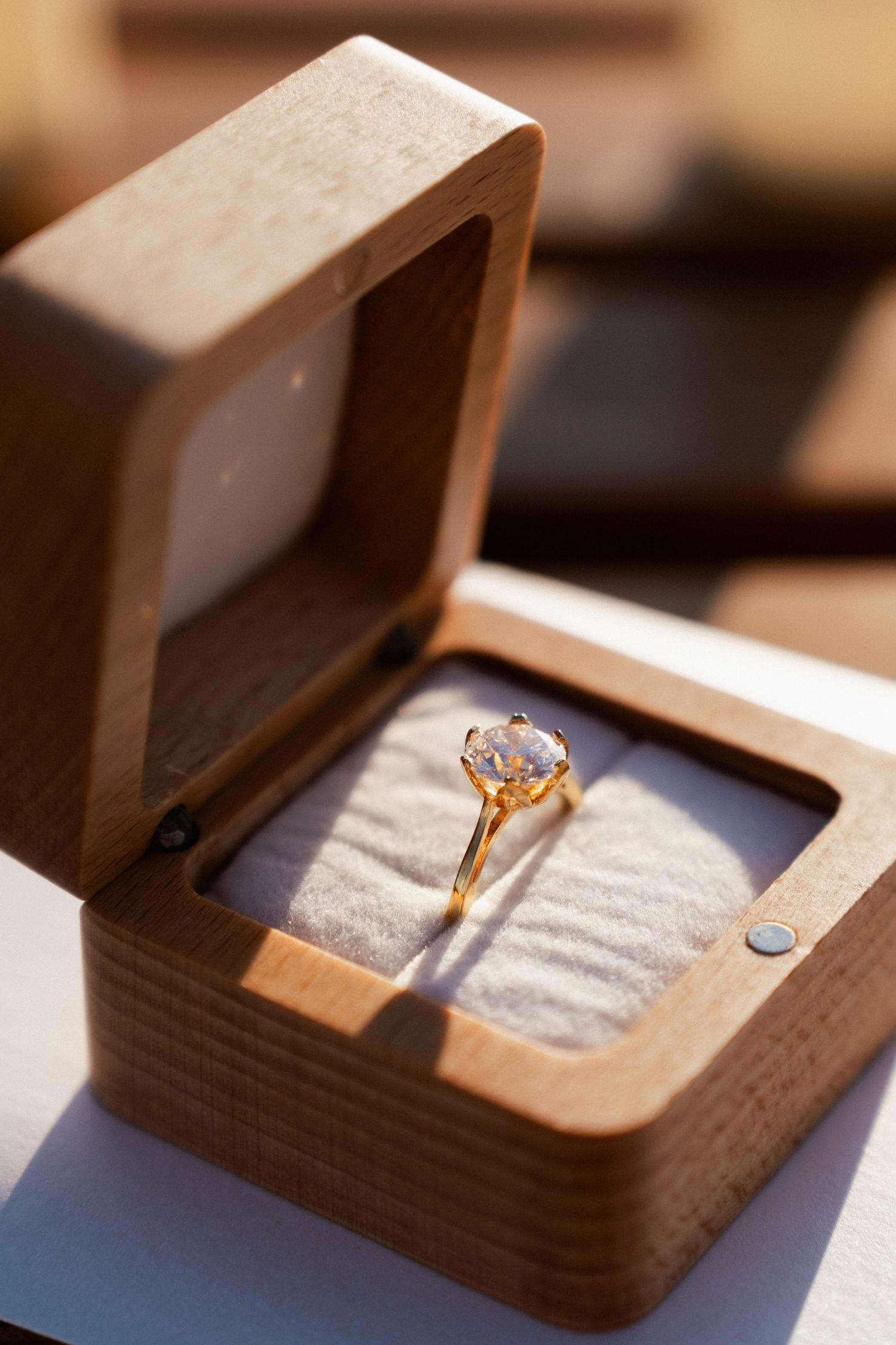 A sparkling engagement ring displayed in an elegant wooden box with velvet lining.