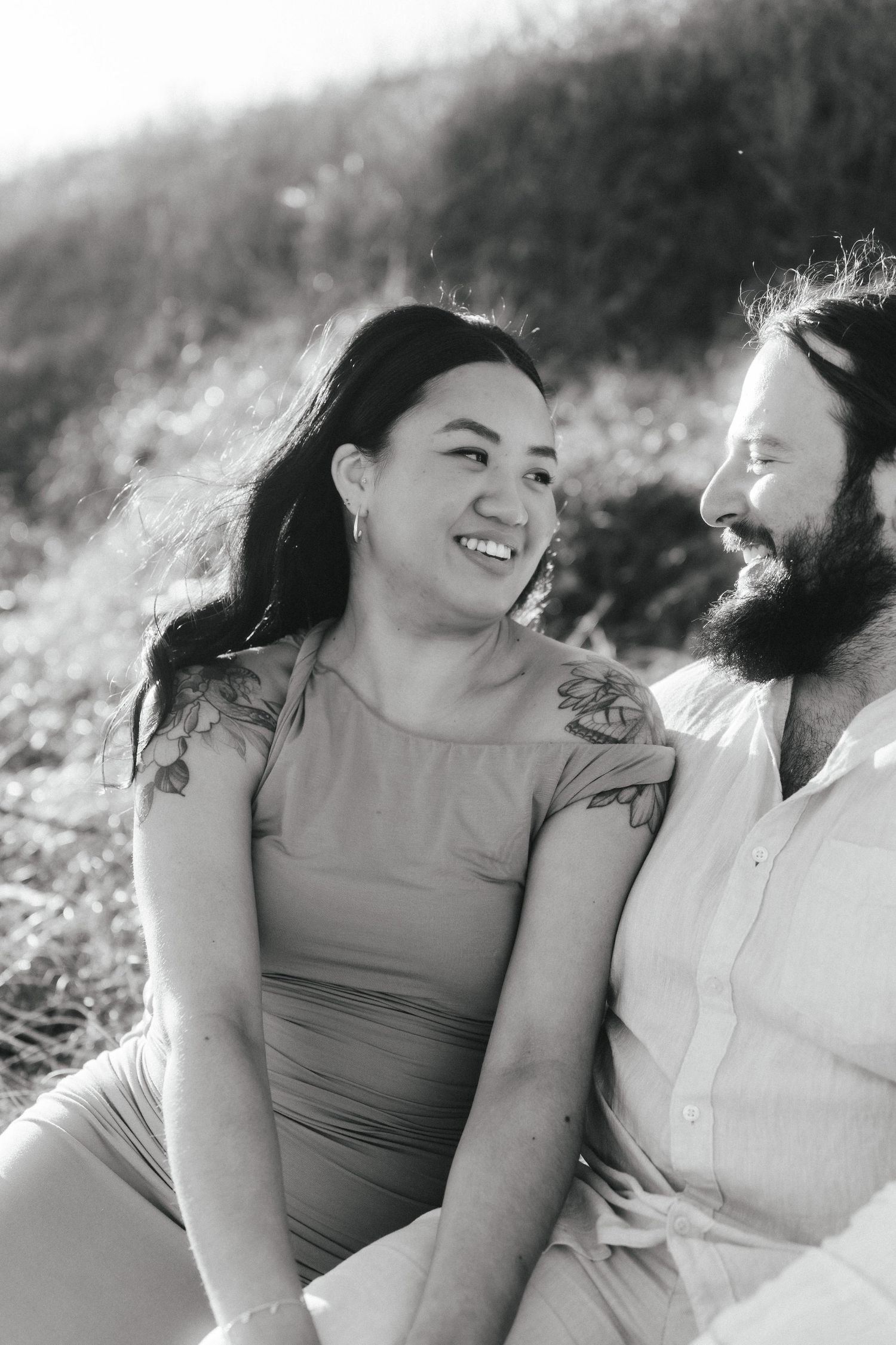 A couple shares a joyful moment together in a sunlit outdoor setting.