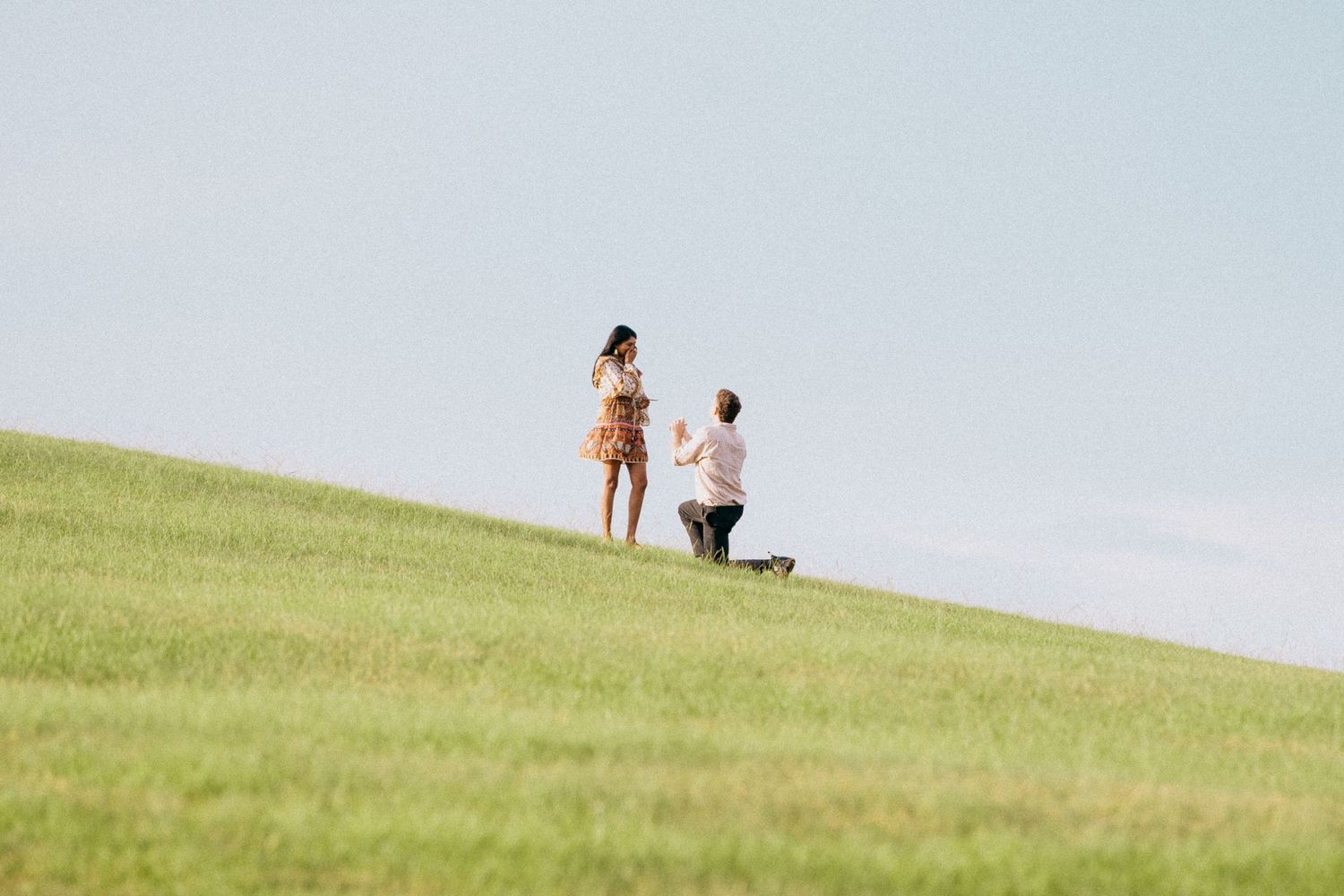 Couple enjoying a sunny day on a grassy hill overlooking the Sydney Opera House.
