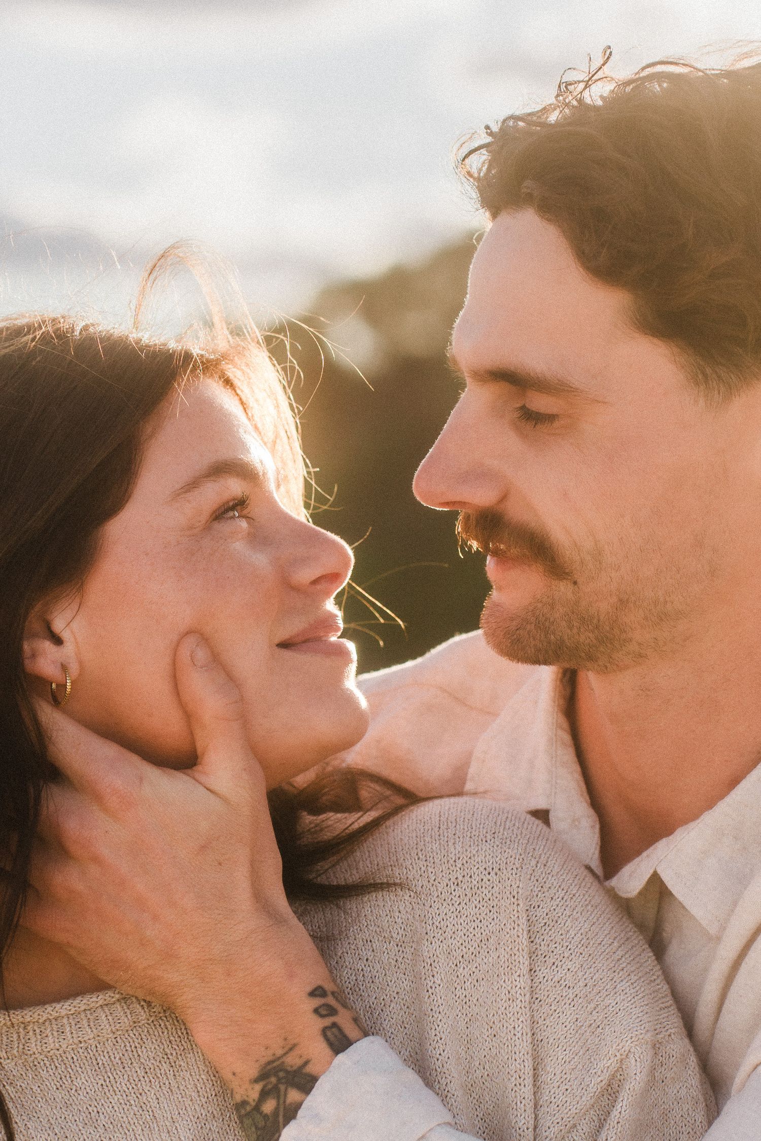 Romantic couple embracing in golden hour lighting with soft expressions of love.
