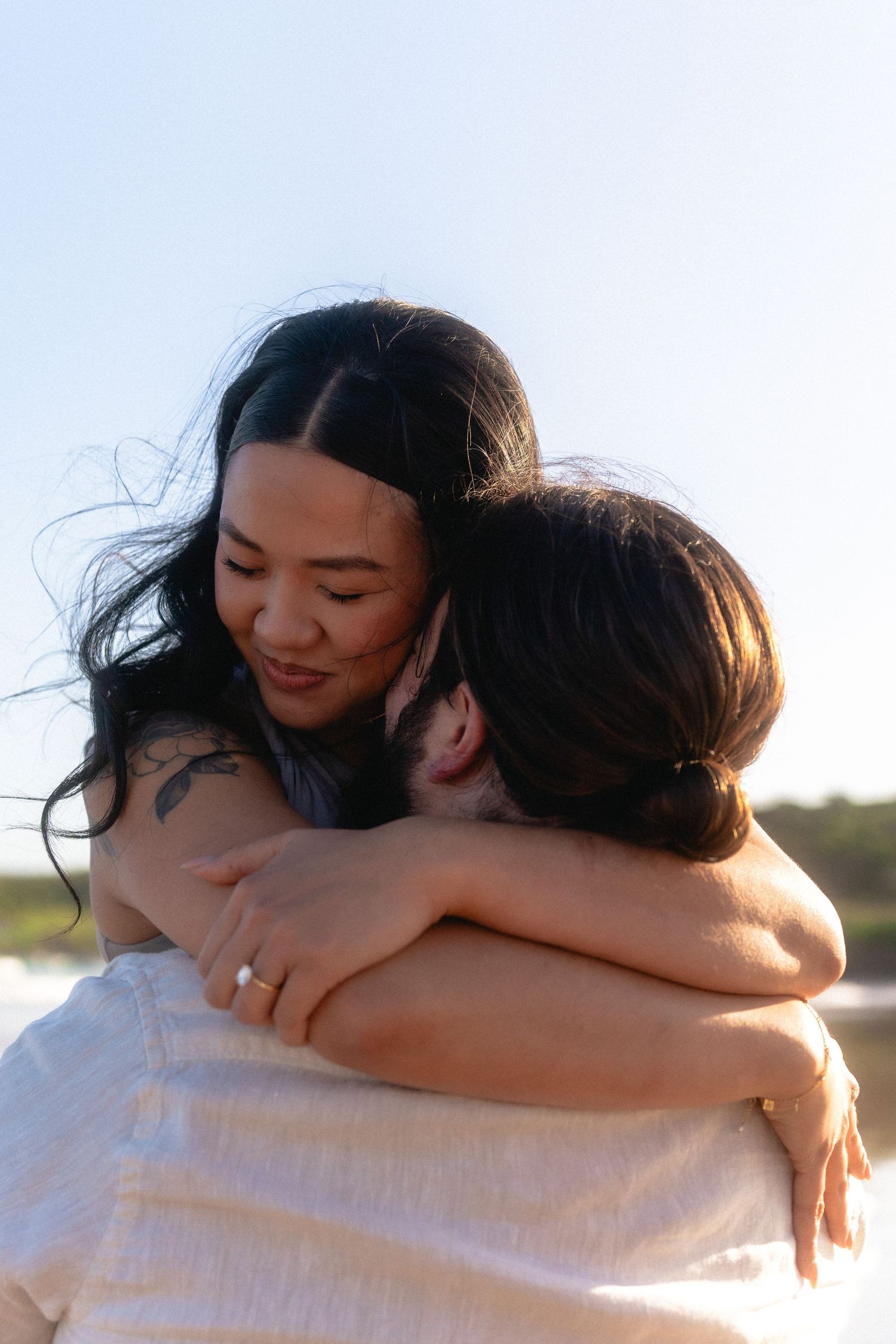 A tender embrace captured in warm sunlight on the beach.
